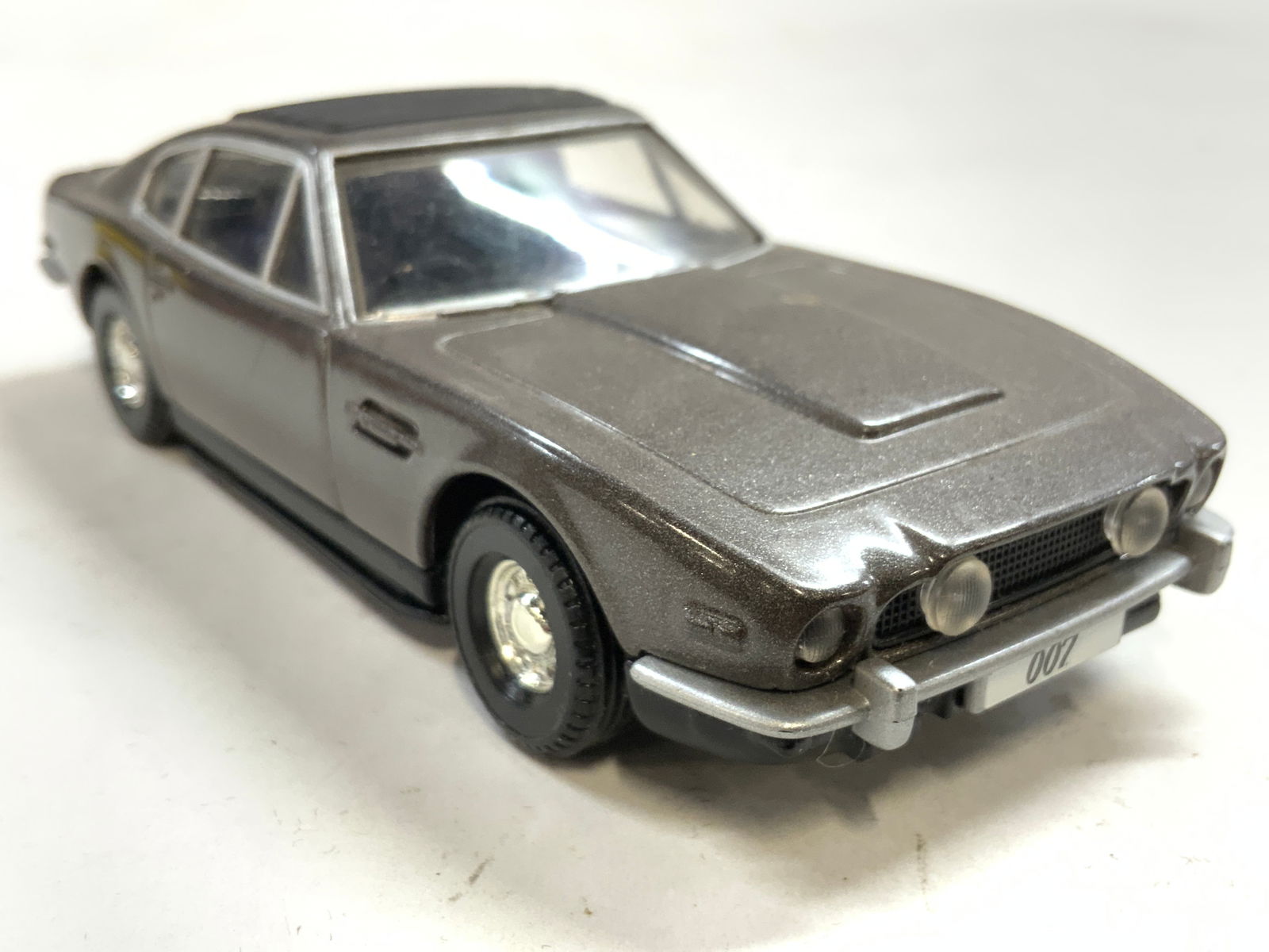 CORGI ASTON MARTIN VOLANTE Die Cast Car: Underside reads CORGI ASTON MARTIN VOLANTE. Die cast car is dark slate toned. License plate reads 007. Piece appears to be vintage. Measures approximately 5.25 inches deep 2 inches wide 1.25 inches ta