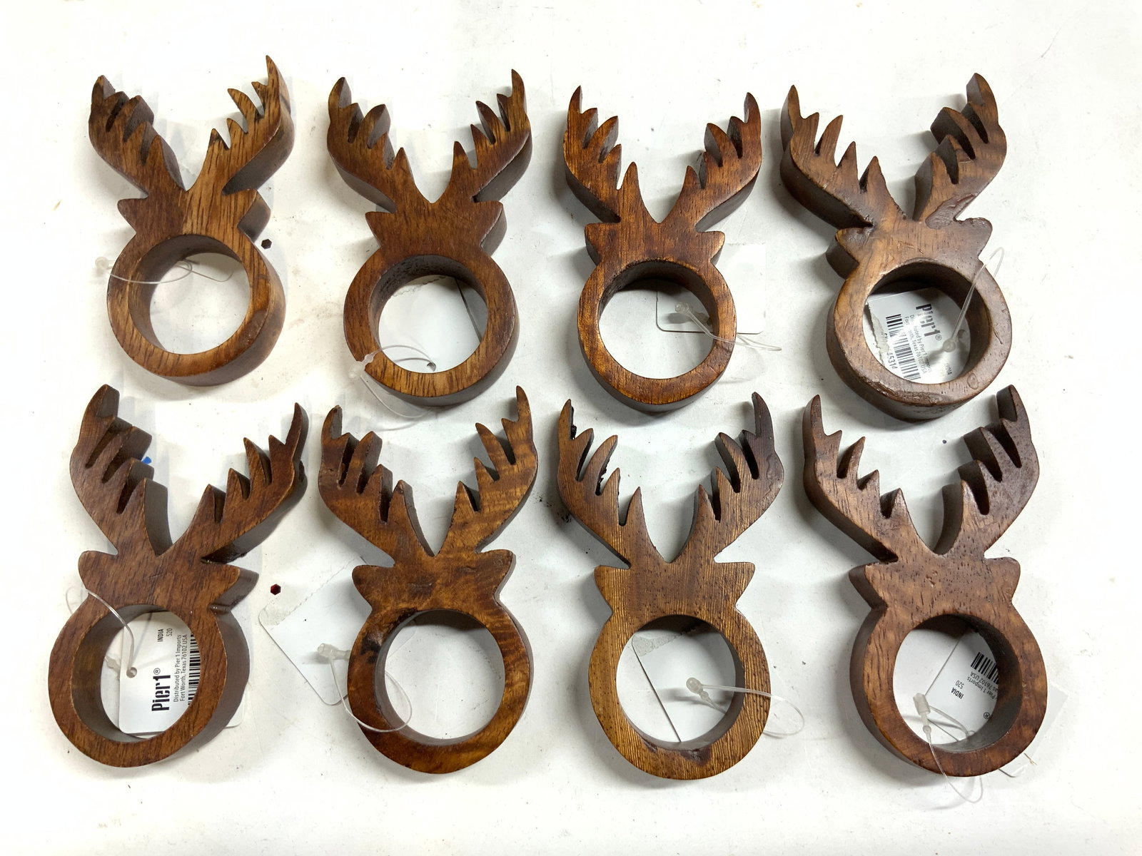PIER 1 8 Carved Wood Buckhead Napkin Rings w Tags: Lot includes 8 napkins rings. Each are brown toned and wooden. Napkin rings each have buck head forms. Each piece has original PIER 1 Tags. Napkin rings each measure approximately 4 inches tall 2.5 in
