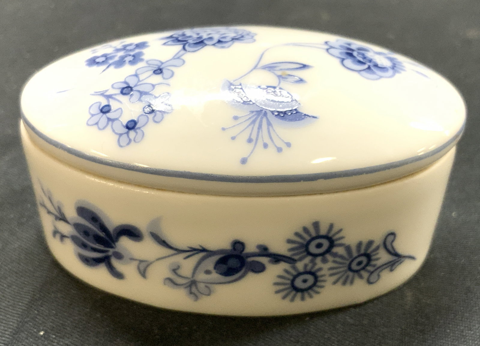 LIMOGES Vtg Porc Trinket Box W Lid FRANCE: Underside is marked LIMOGES FRANCE. Trinket box is white toned and porcelain with blue toned floral and leaf detail. Piece includes lid. Box has oval form. Piece measures approximately 2.5 inches long