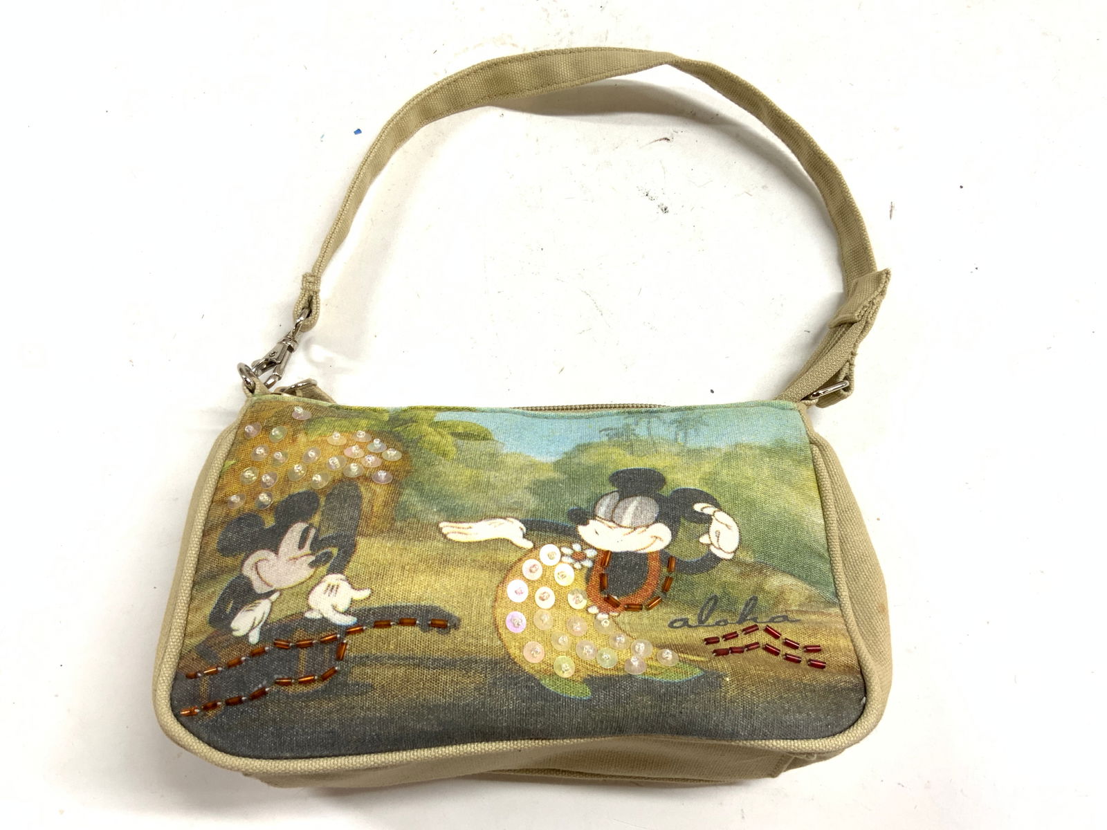 Vntg Mickey & Minnie Mouse Zippered Clutch W Strap: Clutch is vintage. Piece appears to possibly be canvas, possibly cotton, clutch has depiction of Disney Characters Mickey & Minnie Mouse in Hawaii. Reads ALOHA. Piece has zippered opening & strap. Clu