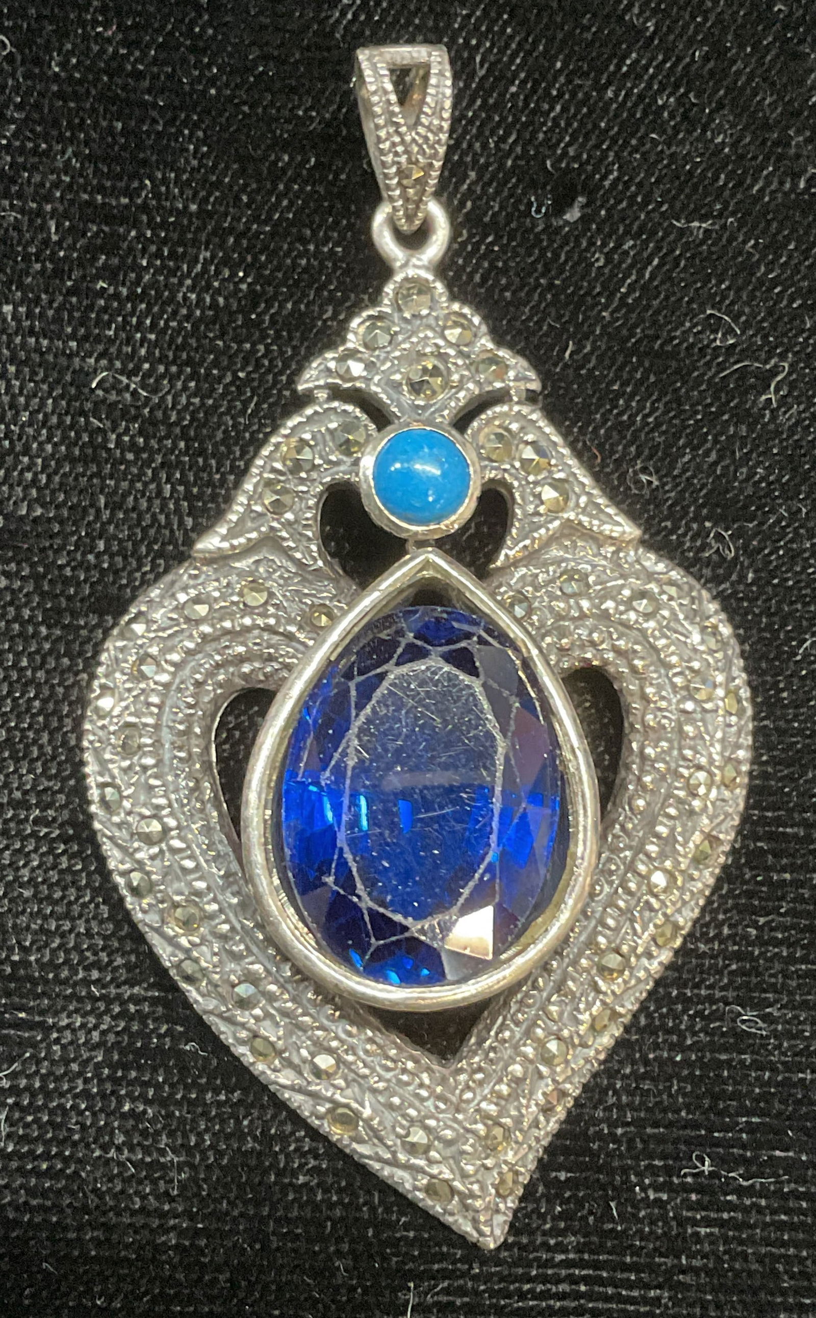 Sterling Silver Crystal Marcasite Heart Pendant: Sterling silver heart shaped pendant with blue crystal and marcasite decoration. Marked 925. Measures approx 2 x 1.25 inches. Total weight 15.2 grams. Some wear including scratching observed. Jewelry,