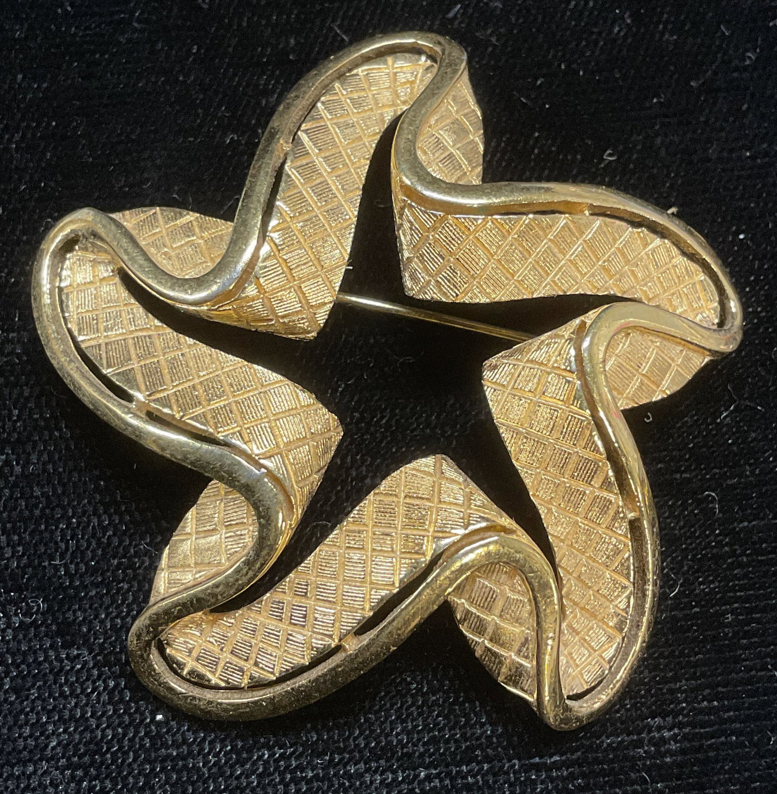 Vintage Trifari Gold Tone Star Brooch: Vintage Trifari gold tone star motif brooch. Textured detail. Signed on underside. Hinge pin on underside. Measures approx 1.75 inches wide. Some wear including scratching observed. Jewelry, estate je