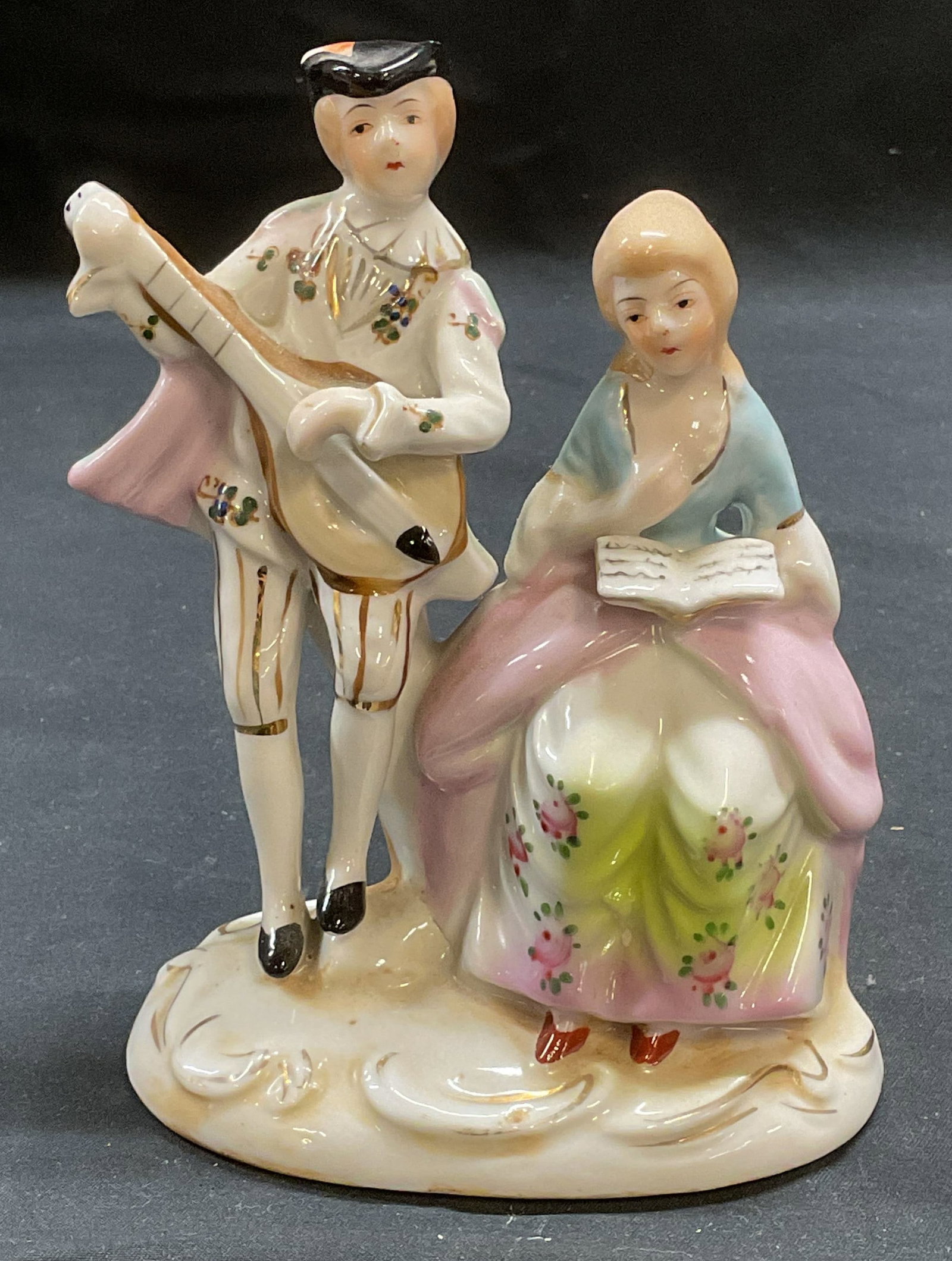 Vintage Porcelain Musician Couple Figurals: Vintage porcelain couple figural. Musician motif. Man with instrument and woman with book. Hand painted. Made in Japan. Measures approx 4.5 x 2.5 x 5.5 inches. Wear including cracks on underside and l
