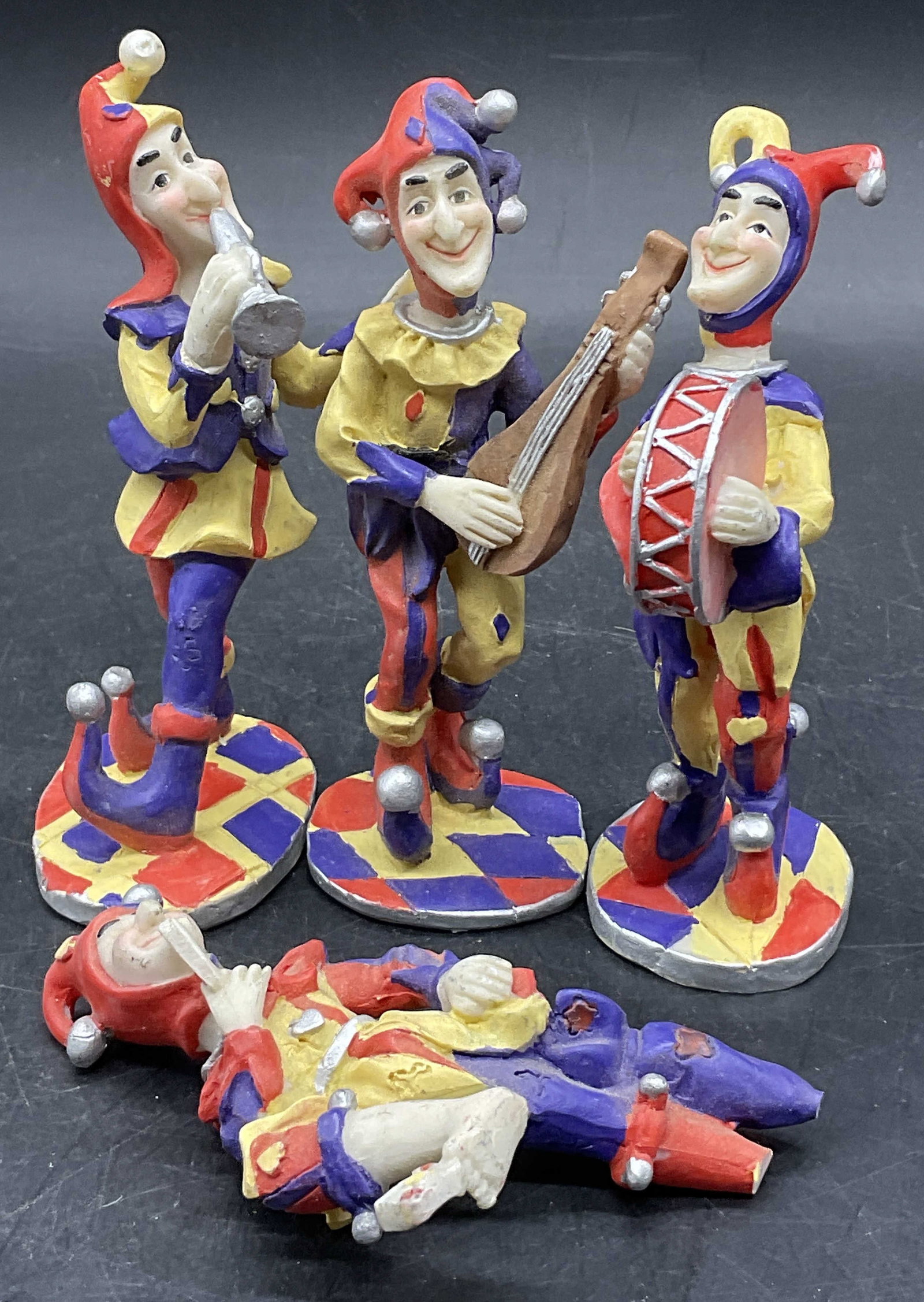 Set 4 Multicolored Musical Jester Figurals: Set 4 Resinous Multicolored Musical Jester Figurals. Measures approx. 4.5H x 1.5W in. Stickers to some undersides. Surface wear present, losses, and chipping present. One piece has no base. home decor