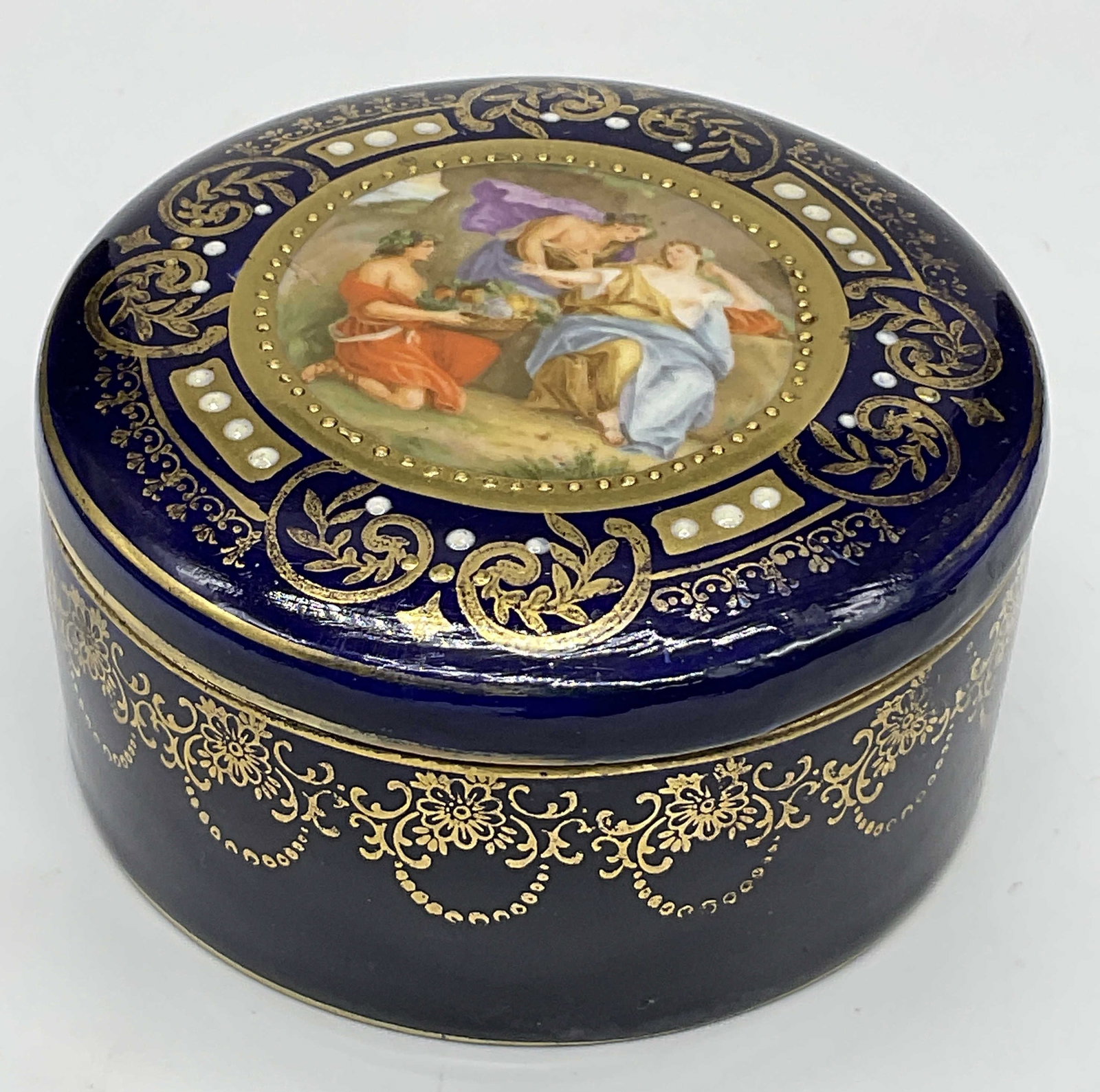 VIENNA AUSTRIA Trademarked Porcelain Trinket Box: VIENNA AUSTRIA Trademarked Porcelain Trinket Box. Cobalt blue with gilt line work, a center scene featuring figures, and raised paint. Lidded. Underside reads Vienna, Made in Austria. Trademarks to th