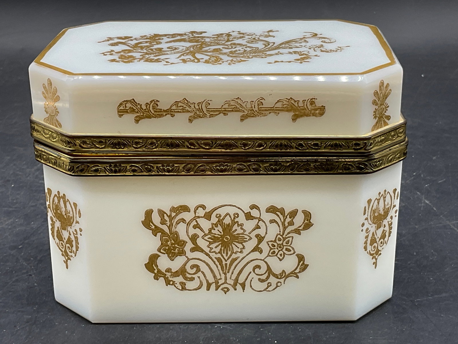 Vintage White Opaline Glass Hinged Lid Trinket Box: Vintage White Opaline Glass Hinged Lid Trinket Box with Gilt Accents. Designs include florals, foliage, birds, and more. Opens with metal hinge hardware. Measures approx. 3.75H x 5W in. Losses to pain