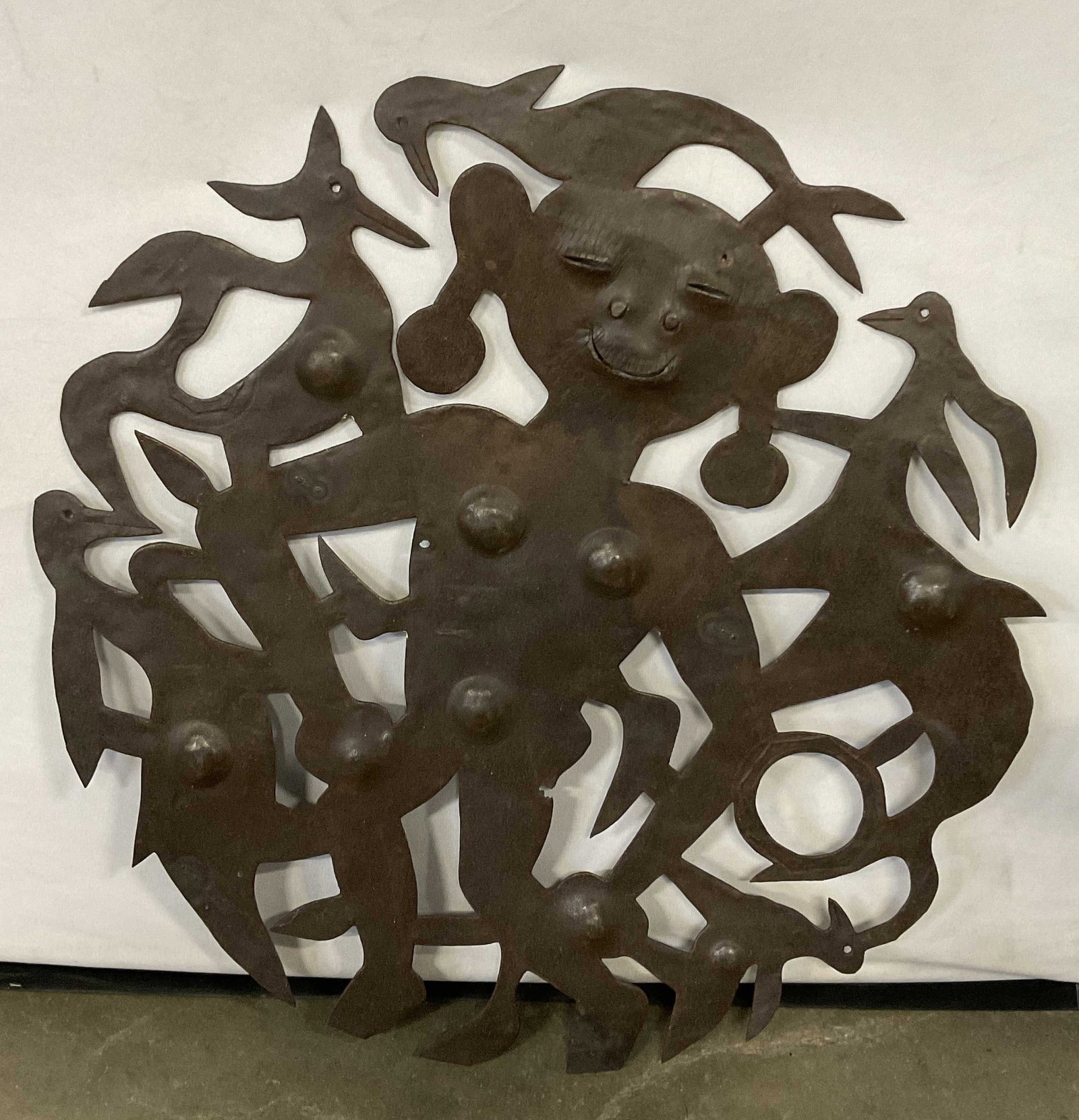 Vintage Pierced Metalwork Figural Wall Art: Vintage Pierced Metalwork Figural Wall Art. A figure is depicted to the center. Various animals surround the figure. Measures approx. 23.5W x 23.5L in. Surface wear, discoloration, and chipping presen