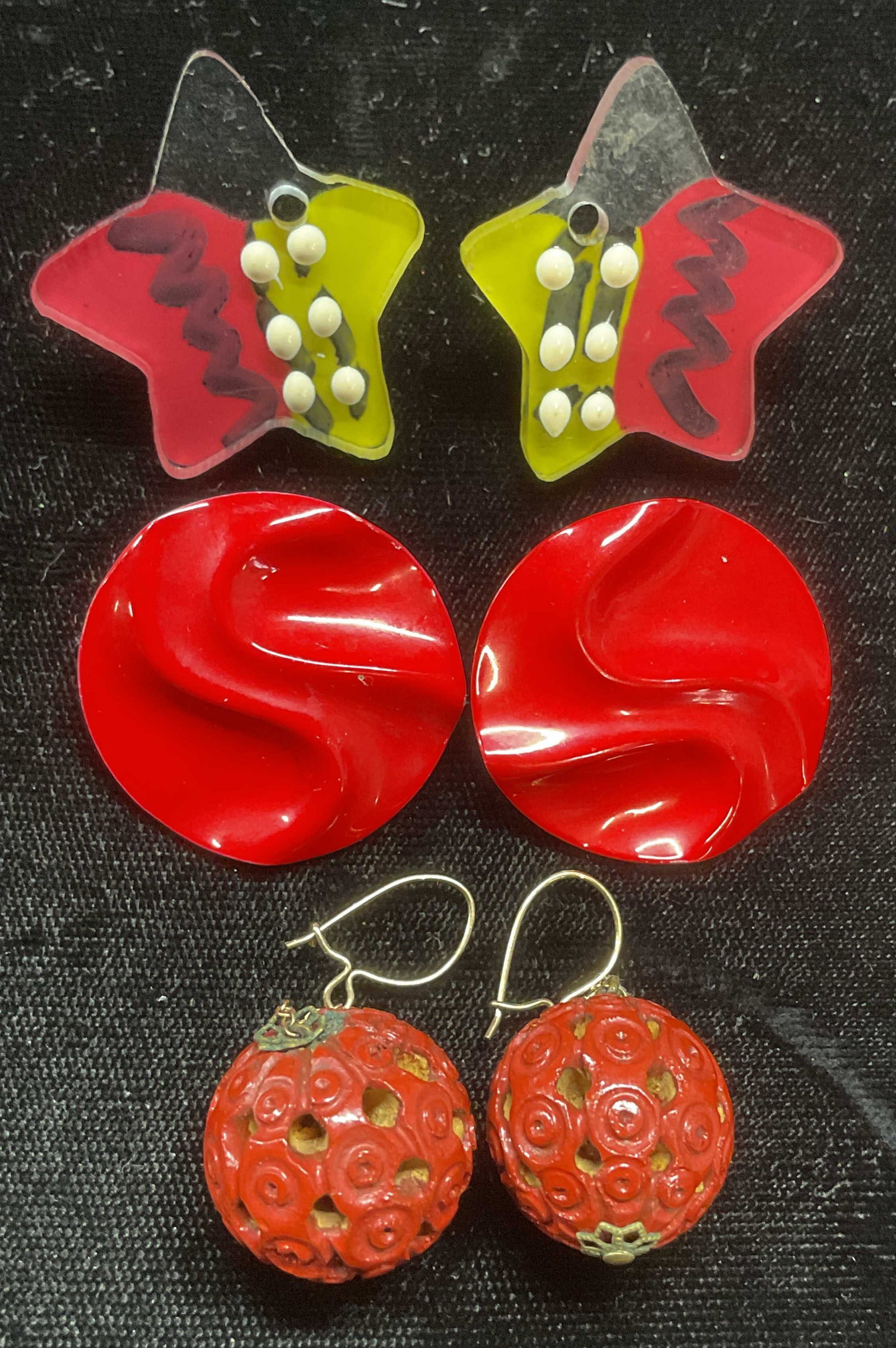 Lot 3 Red Enamel, Star, Ball Earrings: Lot of 3 pairs of earrings. Acrylic star shaped earrings, red enameled wave earrings, and red ball drop earrings. Largest approx 1.25 inches long. Some wear to all including scratching observed. Jewel