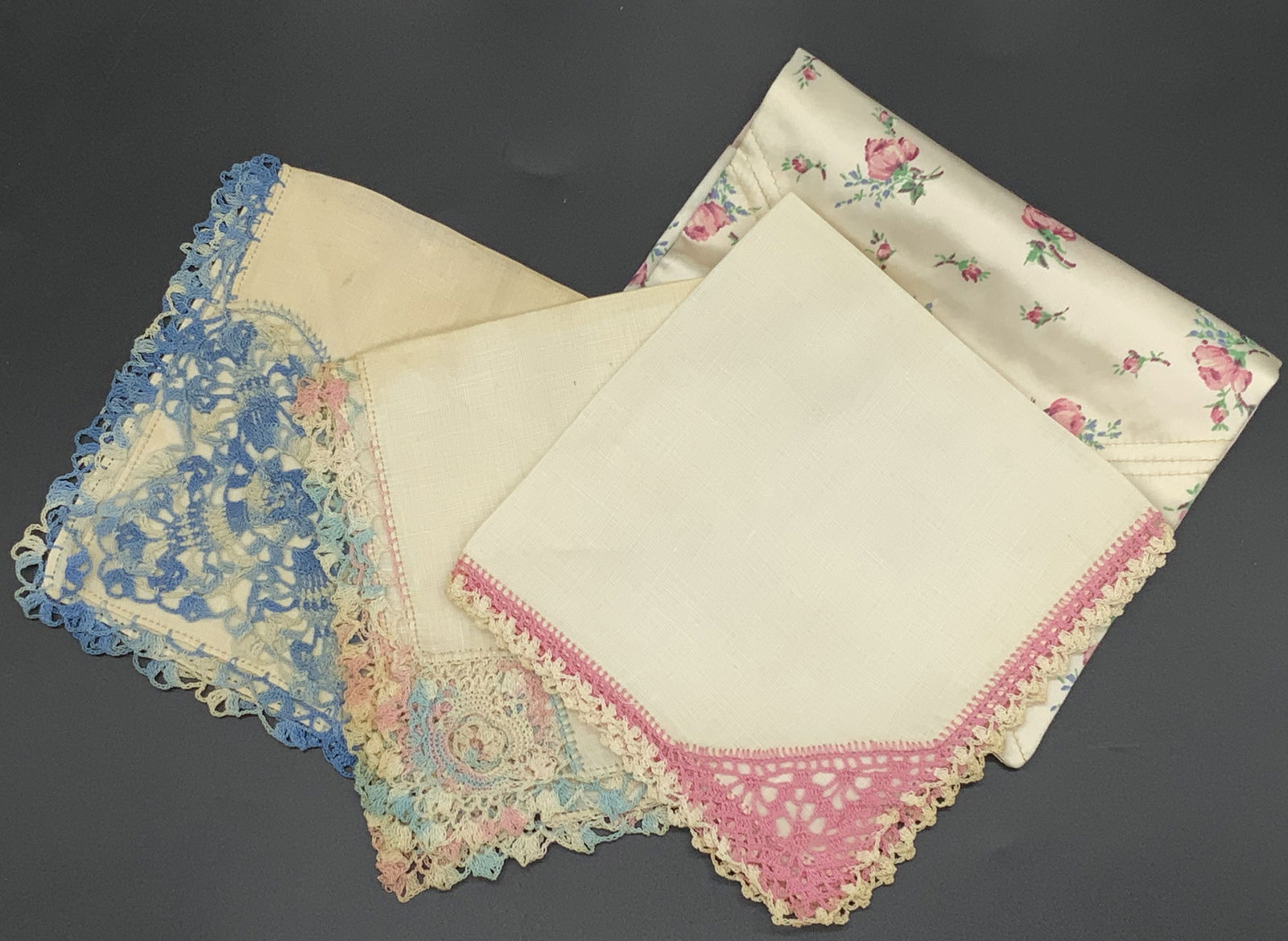 Lot 4 Handkerchiefs in Fabric Pouch: 3 handkerchiefs and 1 fabric carrying pouch. Handkerchiefs have embroidered trim detail in tones of blues, cream, and pink. Measures approx 12 in square. Evident wear and discoloration. Fashion, weara