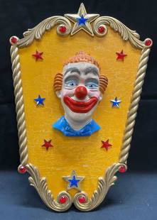 Sgn Ellie Haggerty Clown Head Carousel Panel: Signed Ellie Haggerty carousel panel. Clown head on panel with star shaped red and blue crystals. Hand painted, orange background with gilt border. Signed on underside. Wood and composite