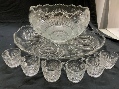 Set 8 Glass Punch Bowl, Cups, & Serving Dish: Lot includes 1 punch bowl, 1 serving tray, & 6 punch glasses with handles. Each piece is glass. Tray & punch bowl have toothed rims. Each piece has intricate geometric relief detail. serving tray