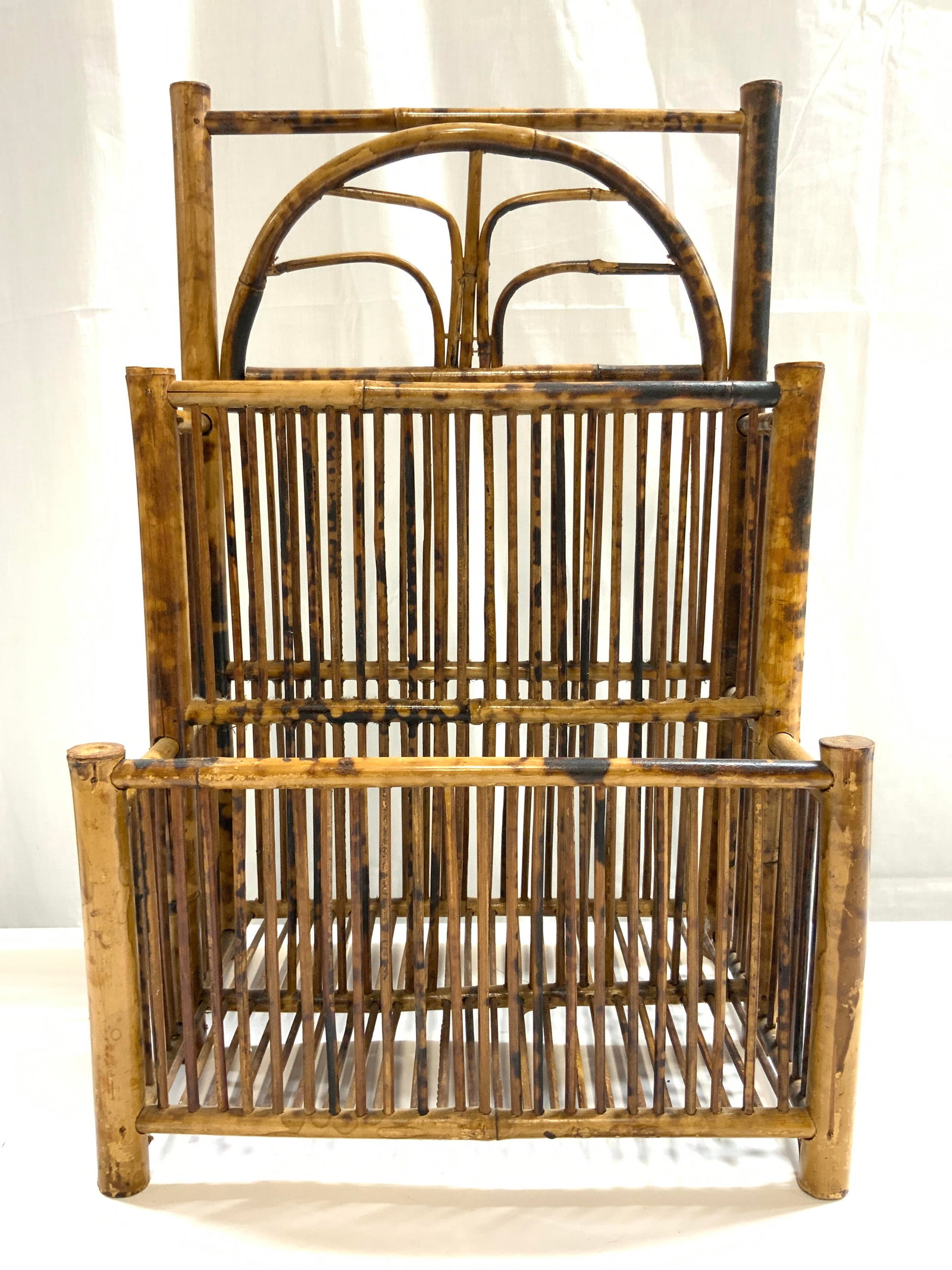 Rattan Bamboo Magazine Rack: Magazine rack rattan bamboo. Piece is tan and brown toned. Magazine rack has 2 sections. Piece has stair style structure. Piece has 4 legs. Magazine rack, newspaper rack, Bamboo magazine rack, bamboo 