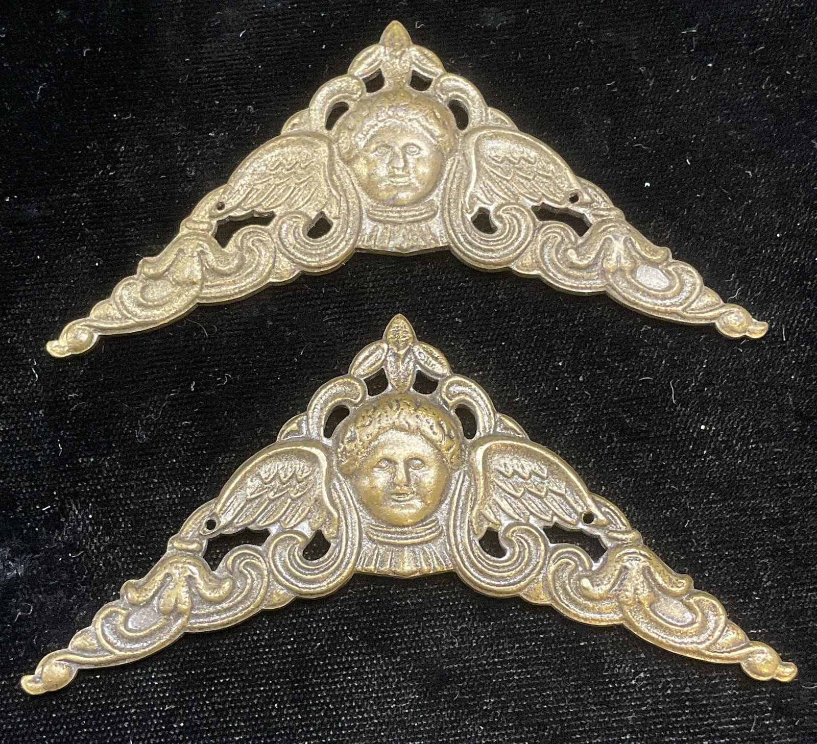 Pair Vintage Metal Cherub Head Corners: Pair of vintage metal corner accent pieces. Raised cherub head and scroll motifs. Measures approx 2.5 x 2.5 inches. Some wear including scratching and patina. Corners, metal corners, cherub corners, s
