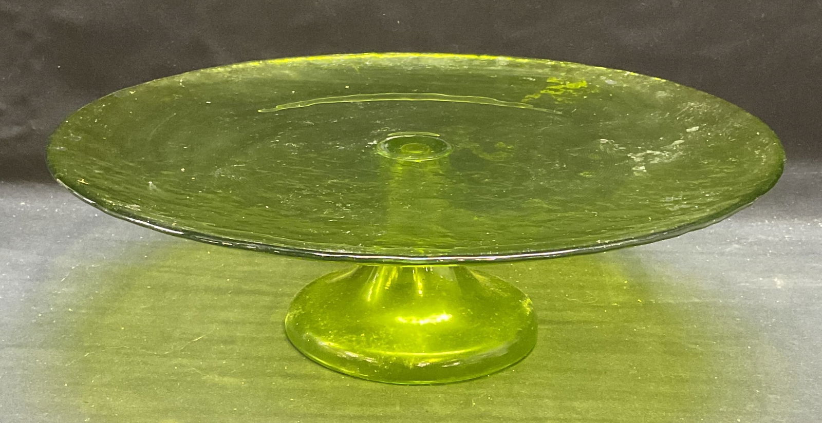 Vintage Vaseline Style Green Glass Cake Stand: Vintage Vaseline glass style cake stand. Textured glass with green finish on per clear glass. Measures approx 12.25 x 3.75 inches. Some wear including loss to finish and scratching observed. Chip on b
