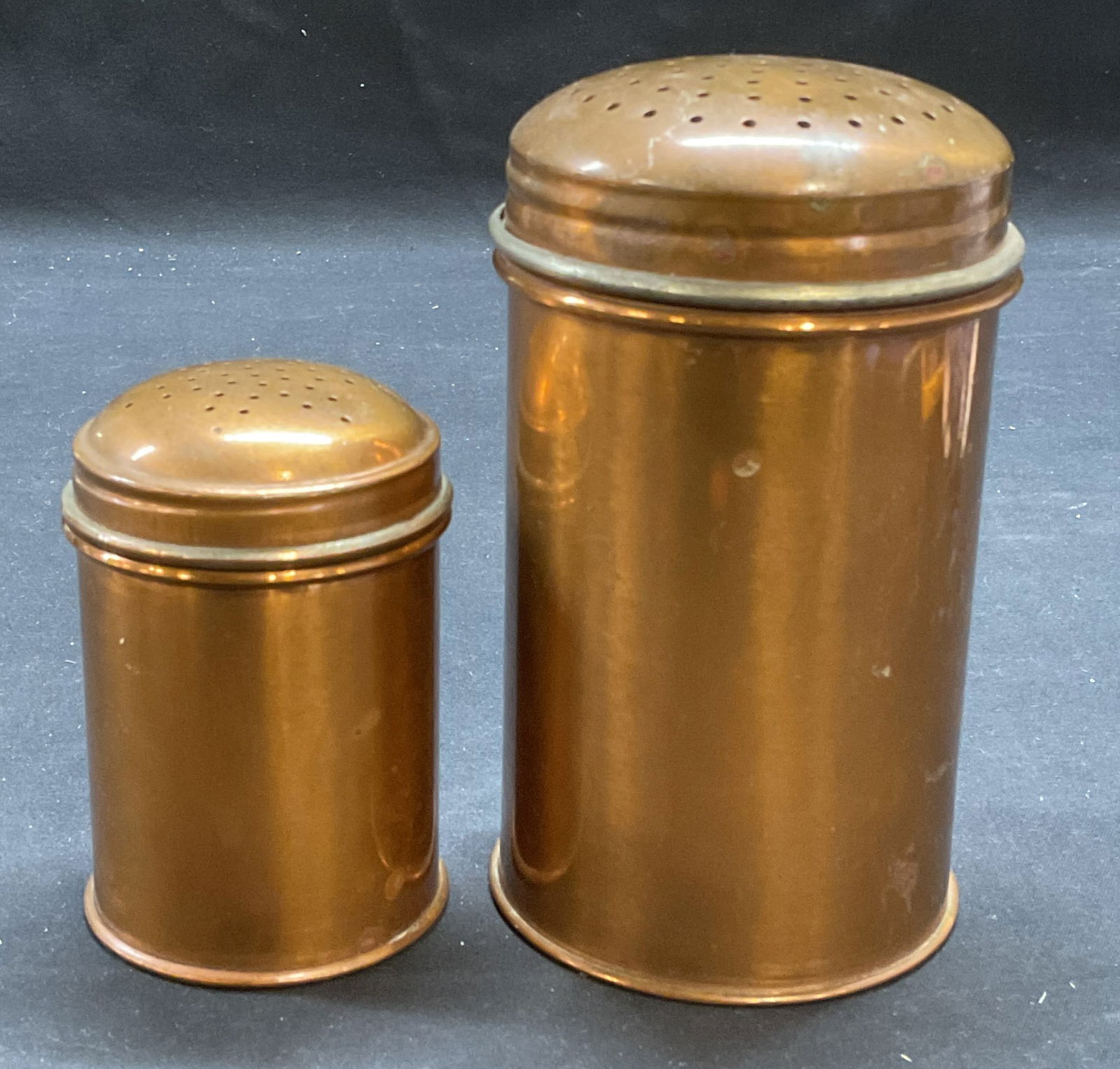Lot 2 Vintage Kreamer Copper Sugar Shakers: Lot of 2 vintage Kreamer copper sugar shakers. Signed on bases. Larger piece measures approx 3 x 5 inches. Both pieces have wear including patina, scratching, and small dents observed. Kreamer sugar s