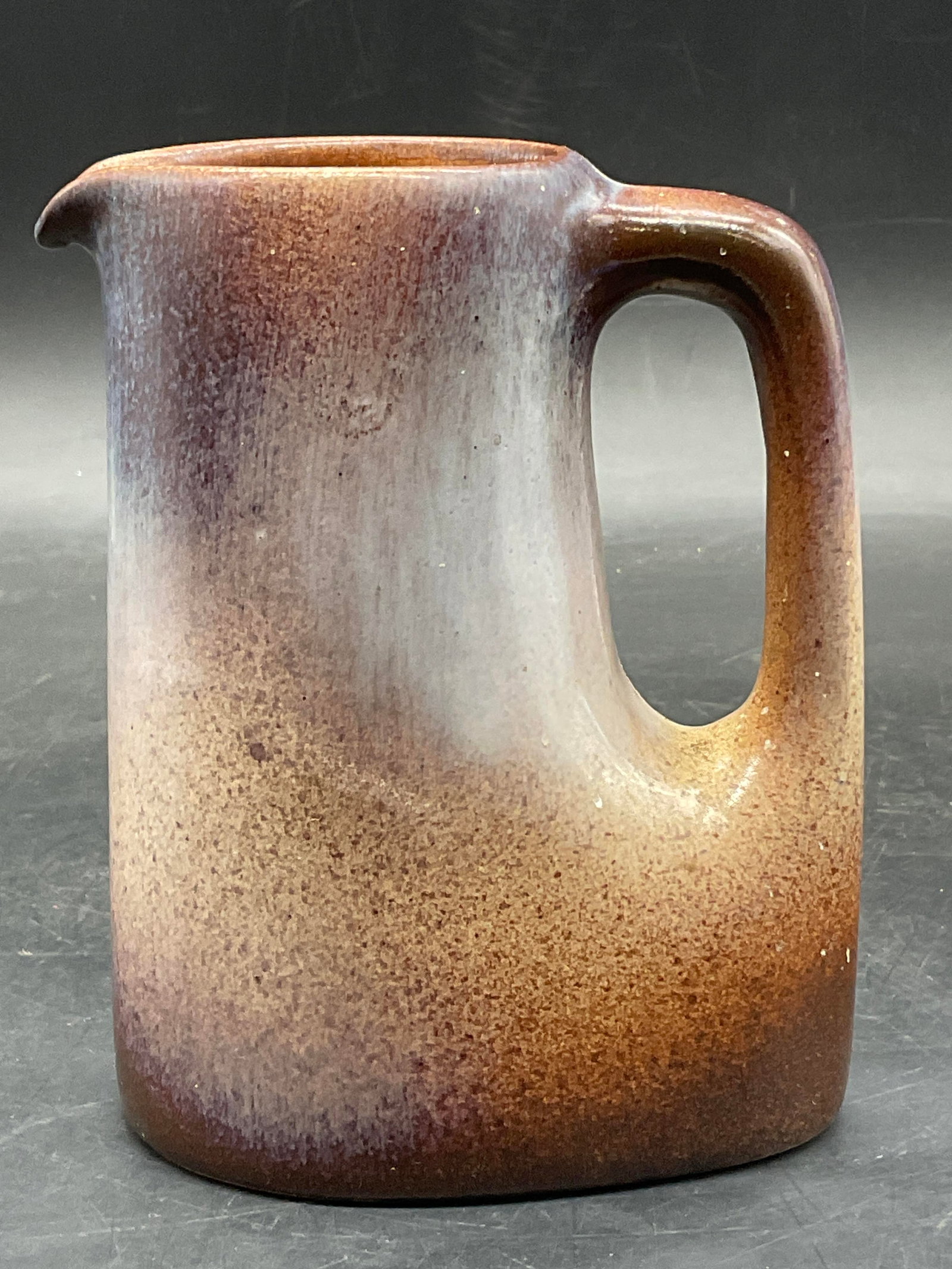 STOCKER Artisan Pottery Glazed Creamer: STOCKER Artisan Pottery Glazed Creamer. Underside signed STOCKER. Measures approx. 5H x 3.5W in. Measured at widest point. Surface wear, residue, and discoloration present. home decor, home accents, h