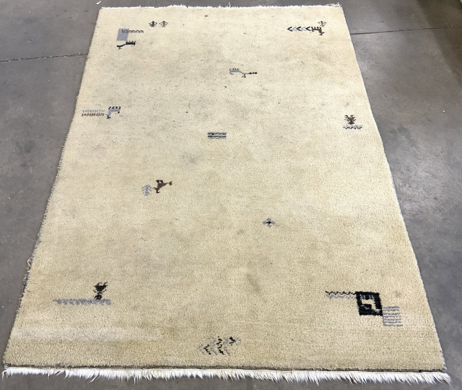 IKEA Wool Pile Fringed Area Rug: Tag on underside reads IKEA Wool Pile. Rug is wool pile. Piece is sand toned with figural, geometric & animal detail. Piece has short cream toned fringes. Rug measure approx 80 inches long 54 inches w