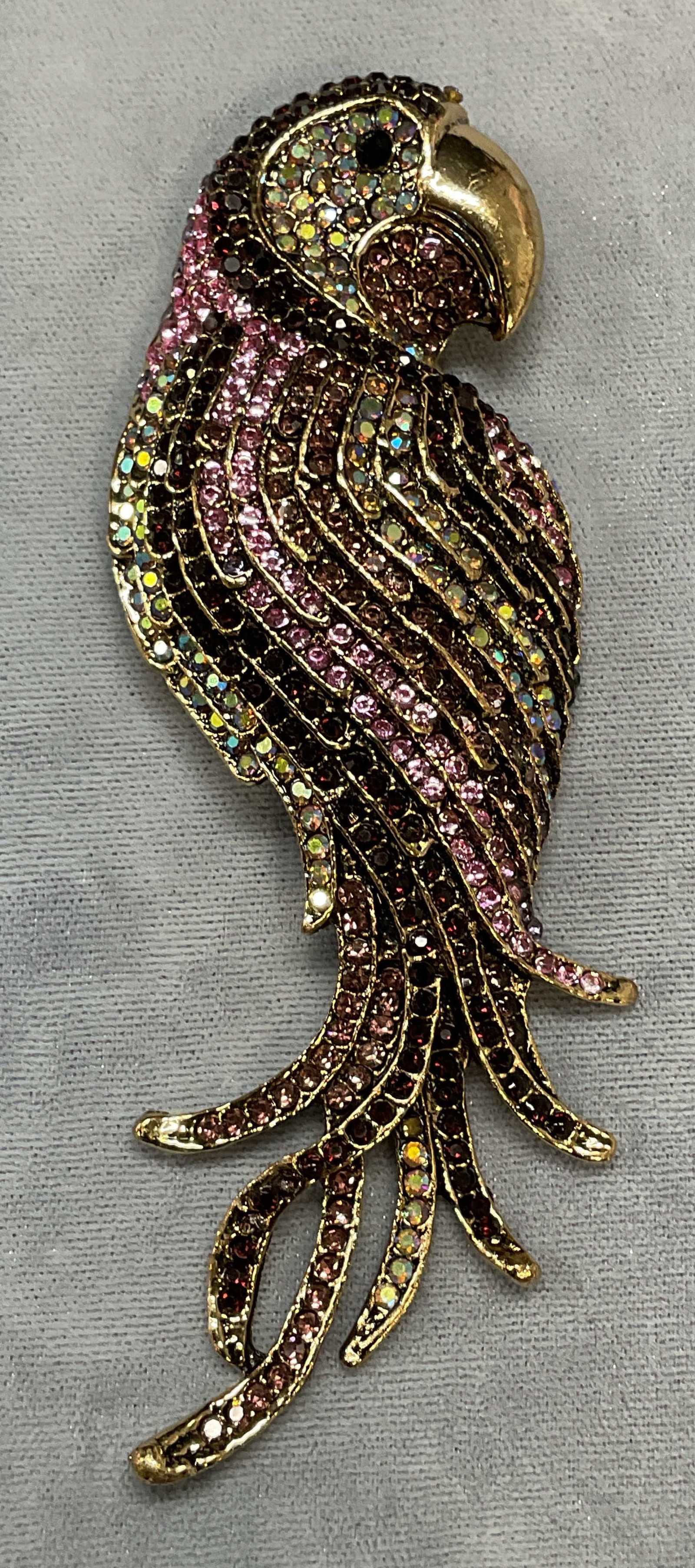 XL Gold Tn Crystal Parrot Brooch Pendant: Gold tone parrot motif brooch/pendant with multicolor crystal decoration. Hinge pin and nail on underside. Measures approx. 4.5 x 1.5 inches. Some surface wear including scratching observed. Jewelry, 