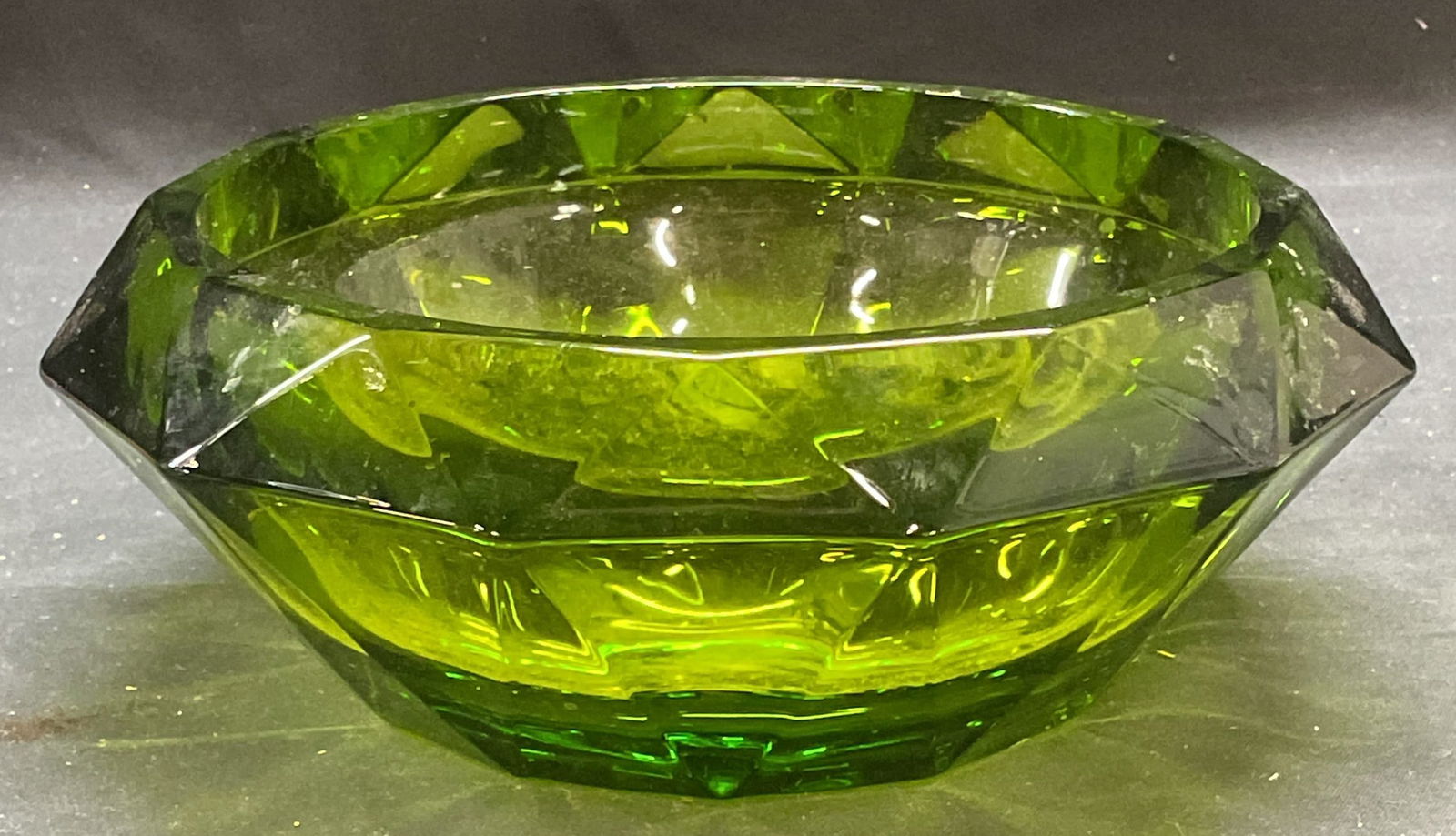 Faceted Emerald Green Art Glass Bowl: Faceted emerald green toned art glass bowl. Thick walled glass, piece has weight. Measures approx 7.5 x 3 inches. Some wear including scratching and small chips observed. Art glass, art glass bowl, gr