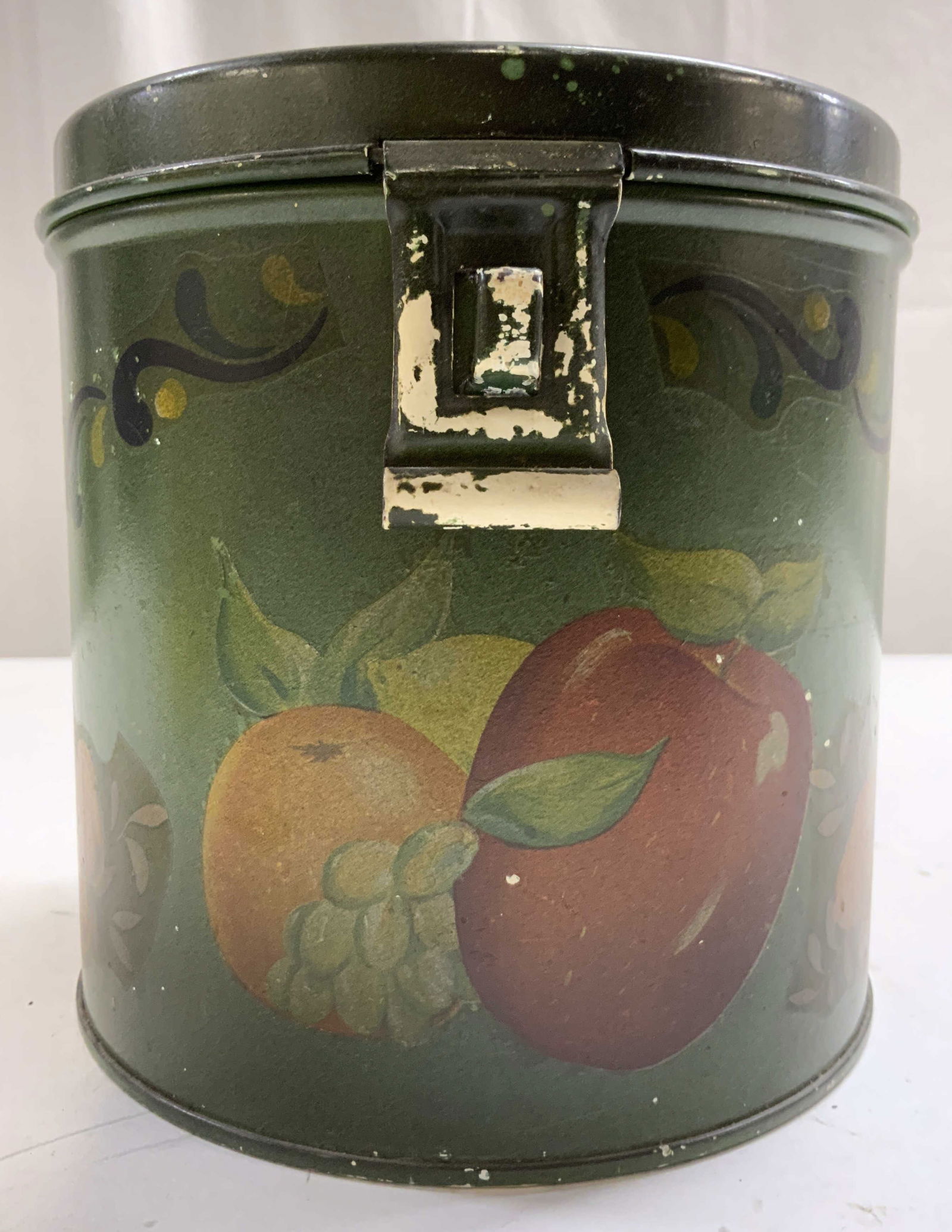 KREAMER Vintage Cylindrical Tin W Lid: Underside is inscribed KREAMER. Tin is vintage. Piece has Cylindrical form. Tin has hinged lid. Piece has multi toned fruit detail. Tin measures approximately 6 inches tall and diameter. Tin, vintage