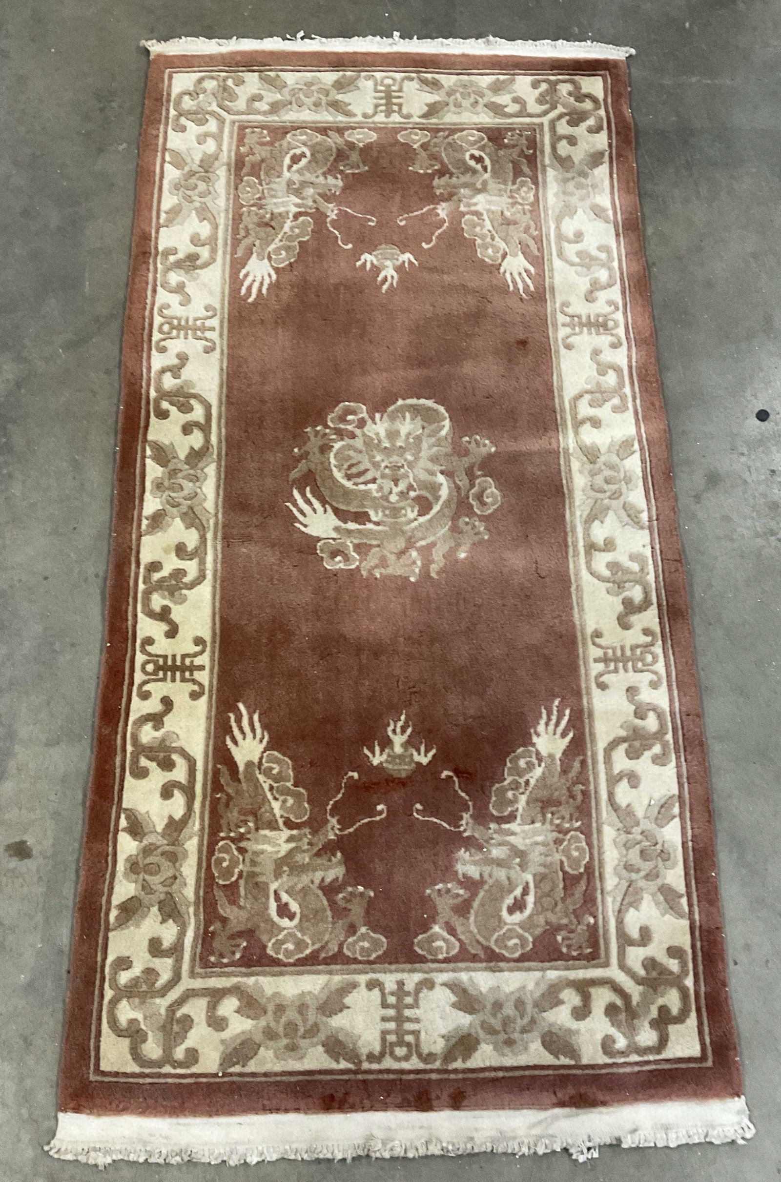 Vintage Oriental Dragon Motif Rug: A vintage oriental dragon motif rug. Asian characters, florals, foliage, and dragon motifs throughout. Fringe trim. Measures approx. 75L x 35W in. Surface wear and discoloration present. Appears to be