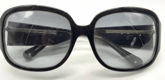 Coach Stamped Sunglasses: Black framed pair of sunglasses with wide lenses, marked Coach on the arms and inner arms, exterior lined with glittering white. Approx 5.5 inches wide, arms being 5 inches, long and lenses