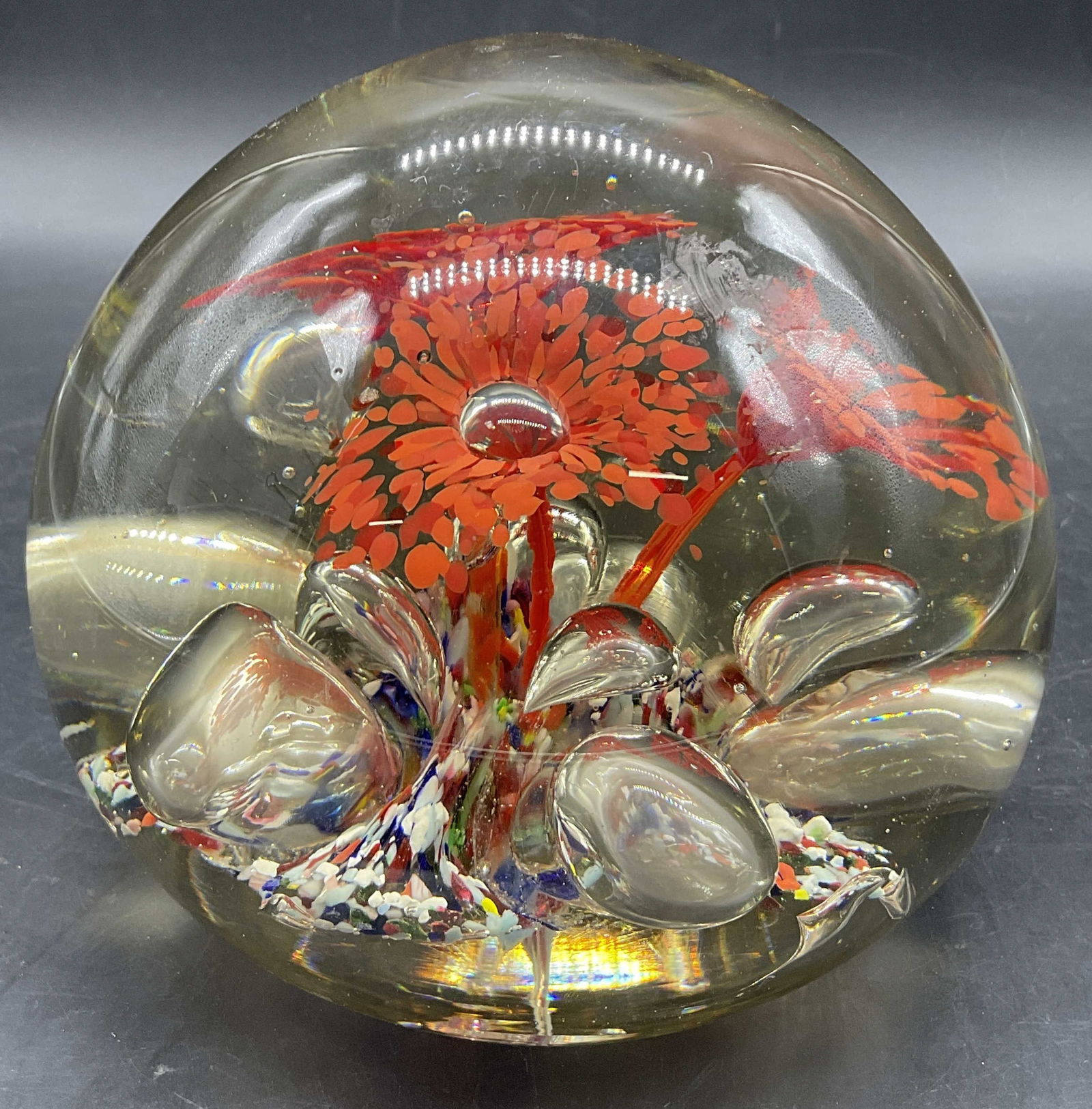 XL Handmade Art Glass Floral Motif Paperweight: Handmade Art Glass Floral Motif Paperweight. Clear dome with multicolored hues to the interior. Thick walled and weighty. Pontil to underside. Rough edges to underside. Surface wear consistent with ag