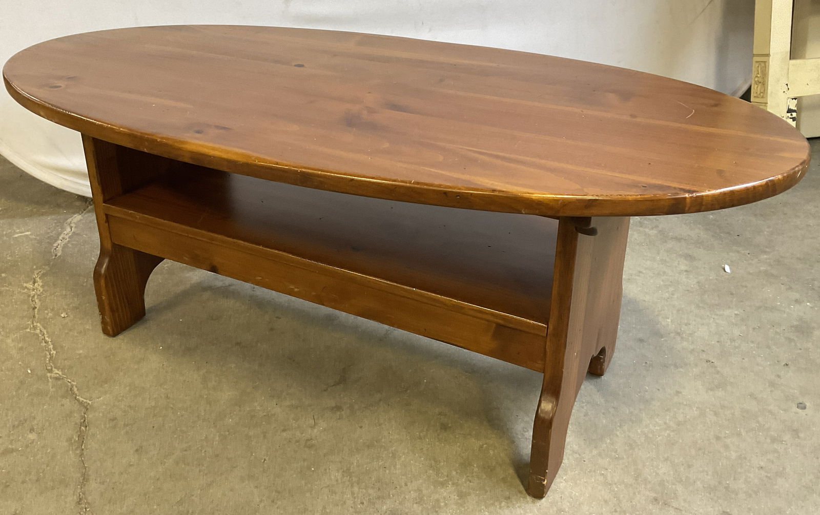 Vintage Oval Form Brown Wood Coffee Table: Vintage Oval Form Brown Wood Coffee Table. Appears to be pine. Shelf below the tabletop for storage. Measures approx. 48W x 25D x 18D in. Surface wear consistent with age, use, and exposure. Chipping