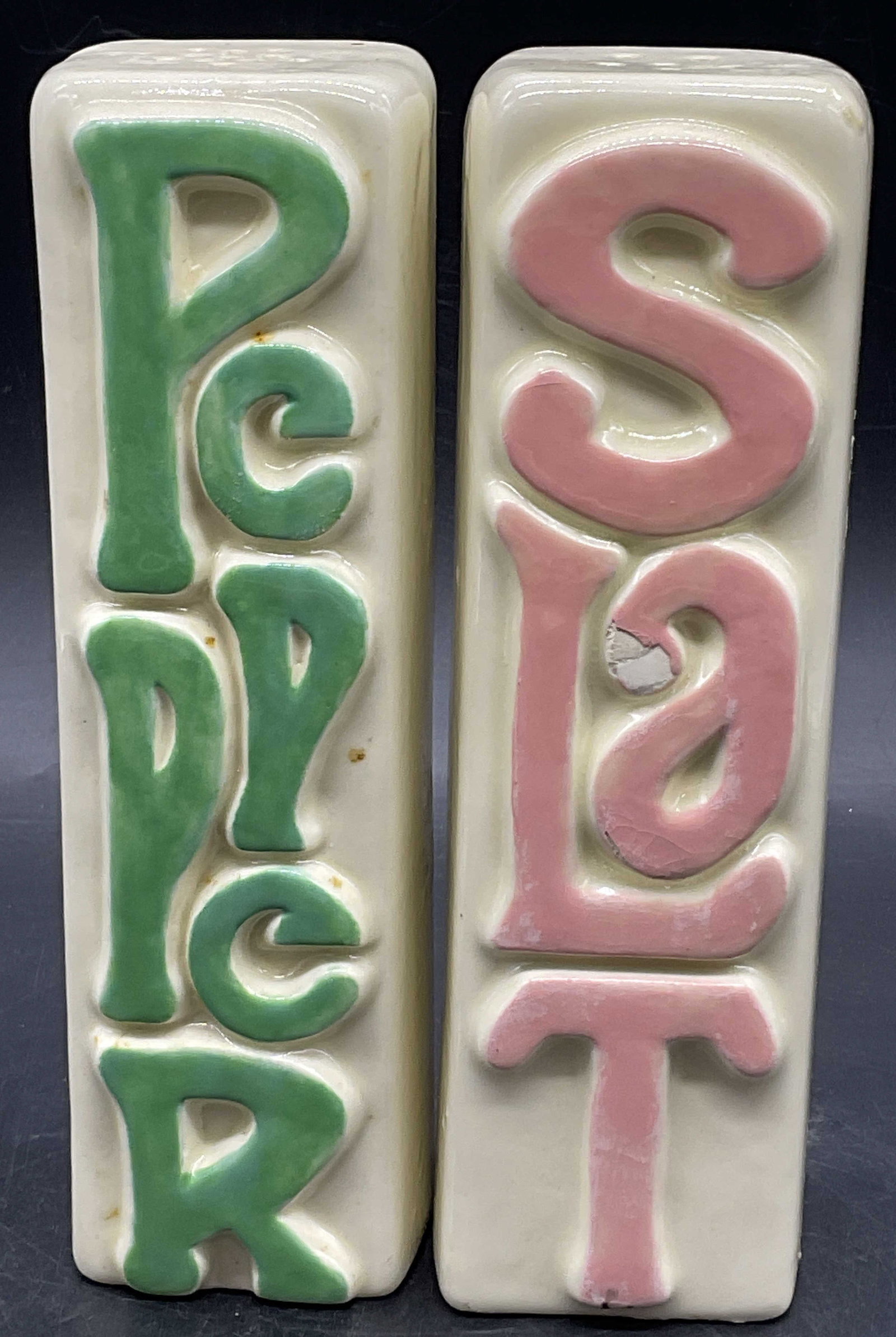 Pr Vintage Ceramic Word Art Salt & Pepper Shakers: A pair of Vintage Ceramic Word Art Salt & Pepper Shakers. Circa 1970s-1980s. Green and pink raised verbiage reading PEPPER or SALT to the obverse and reverse. Measures approx. 7H x 2W in. Surface wear