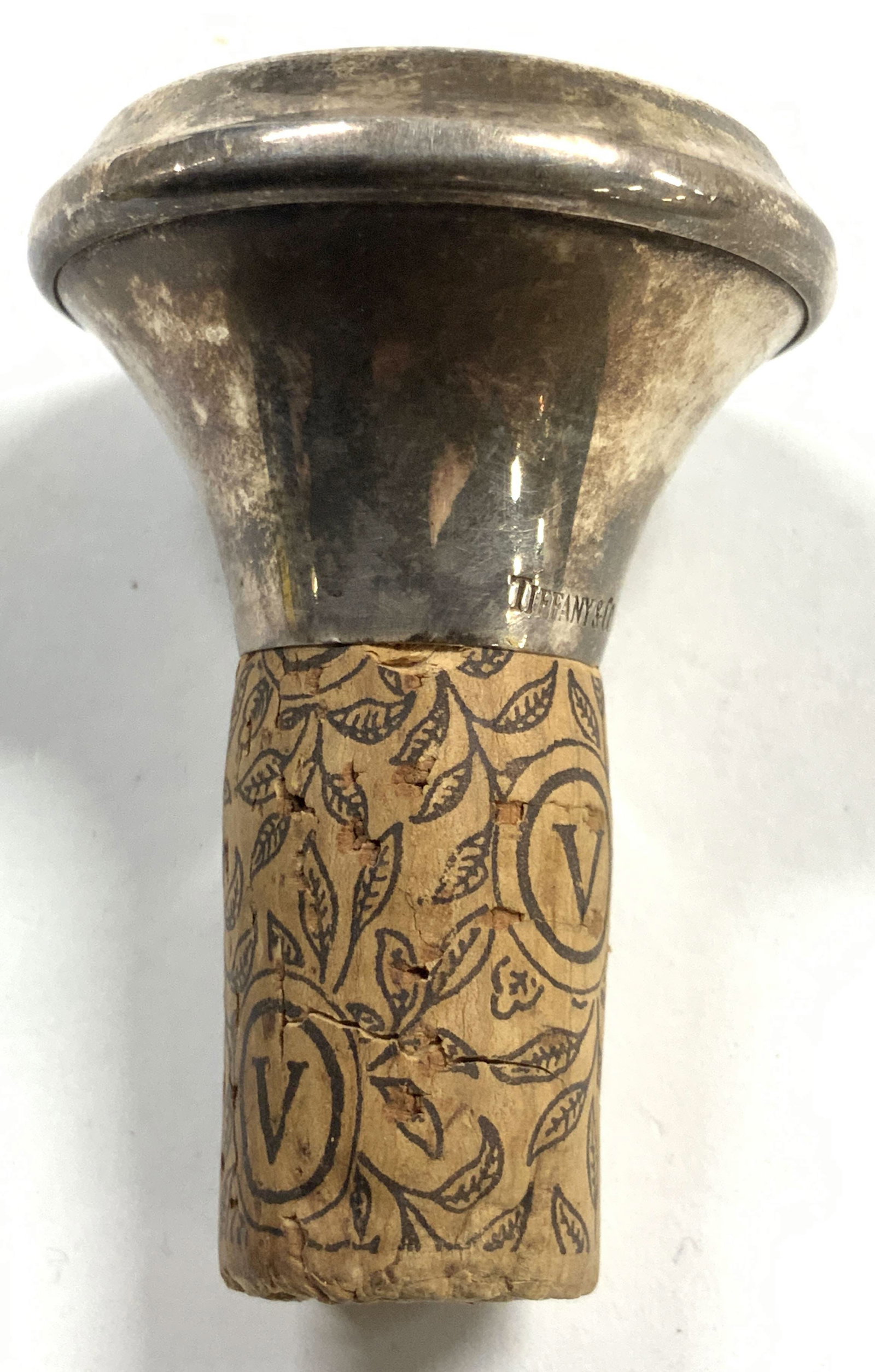 TIFFANY & CO Sterling Silver & Cork Stopper: Stopper is inscribed TIFFANY & CO 925 STERLING GERMANY. Stopper has cork area with brown toned vine, leaf & V pattern detail. Stopper appears to be vintage. Piece measures approximately 2.25 inches ta