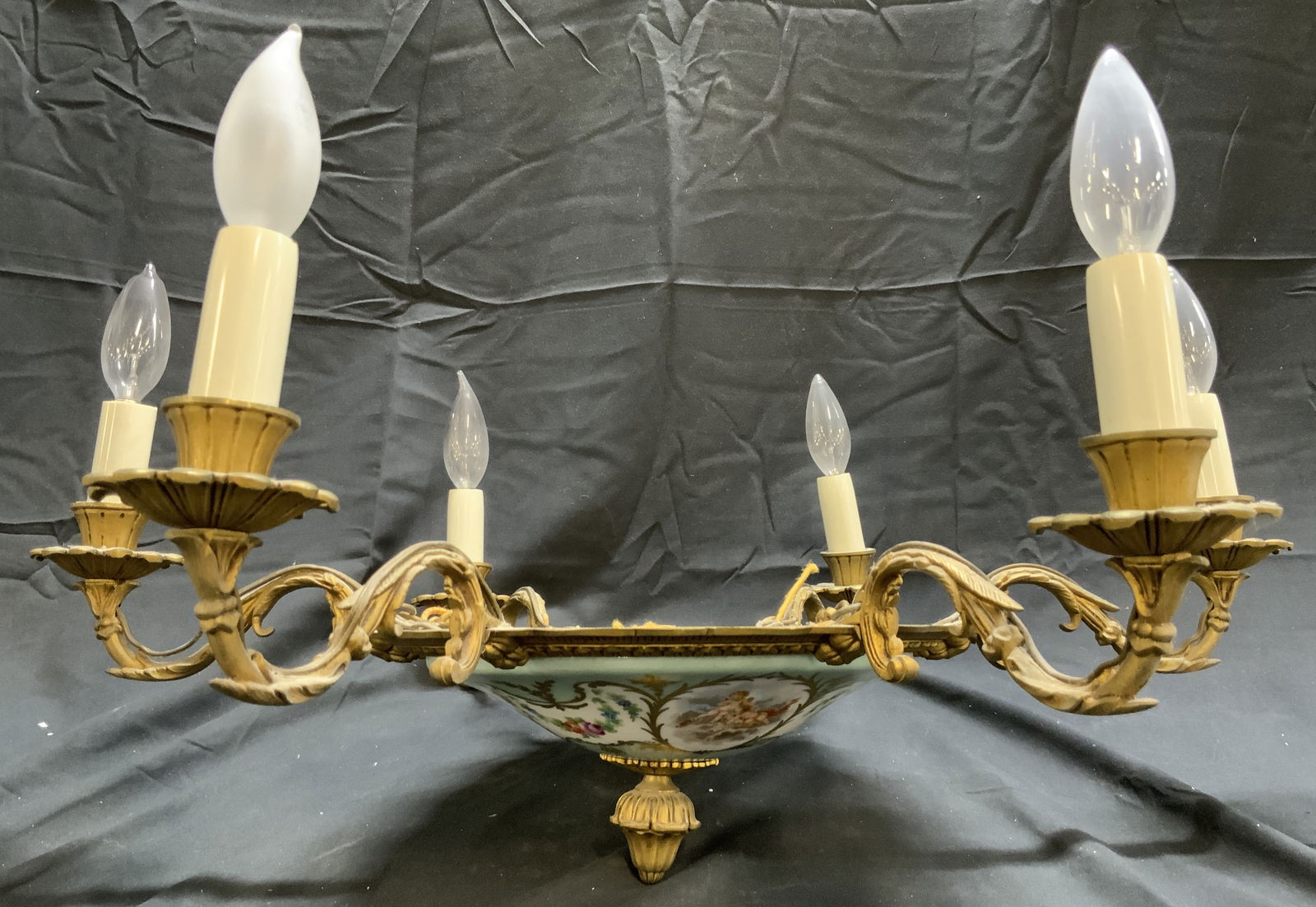 Vntg French Empire 6 Arm Ornate Brass Chandelier: Chandelier is vintage. Piece has 6 S scrolled brass arms. Bottom of piece has finial. Chandelier has glass areas with intricate multi toned floral, leaf, & cherub detail. Piece has candlestick style b