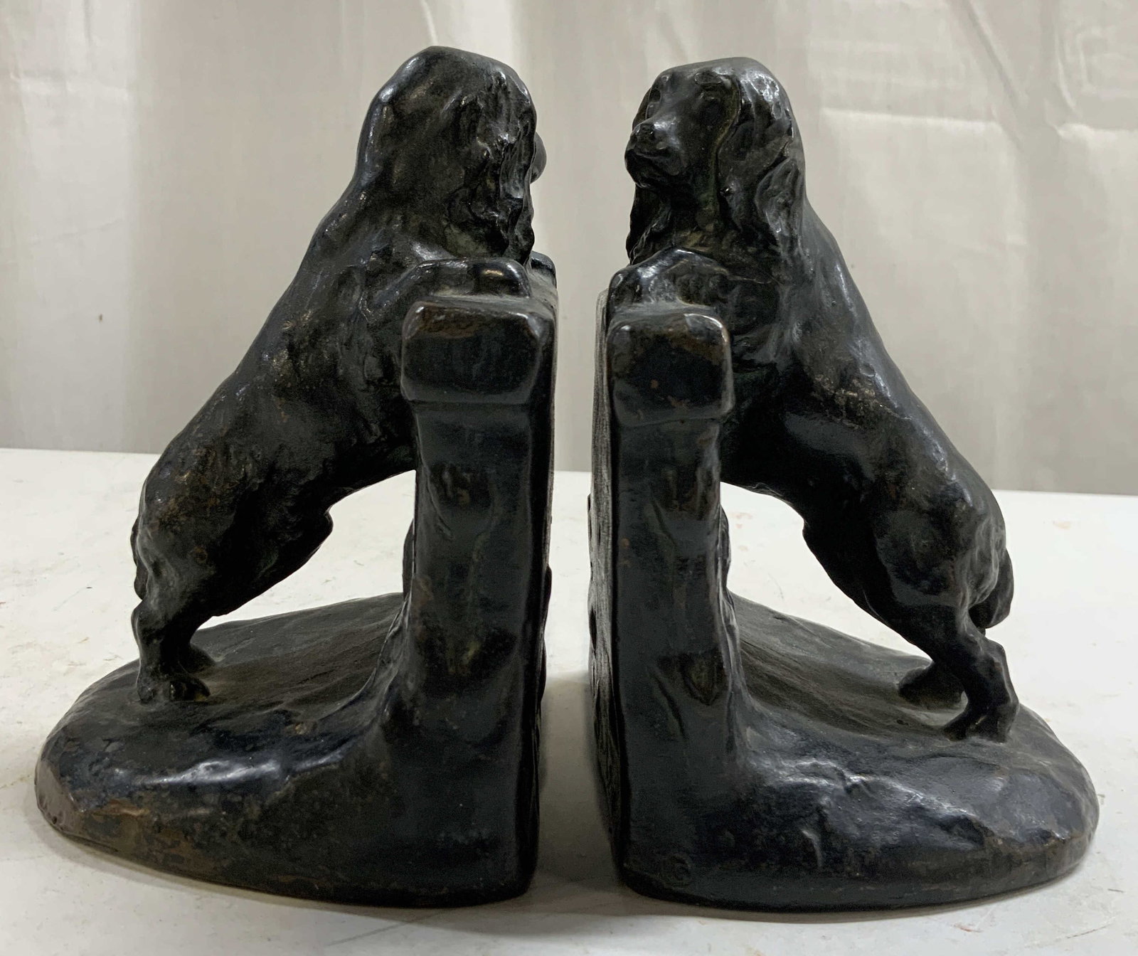 Signed Coppered Basset Hound Bookends: Bookends are signed illegibly. Each piece is black with coppered areas. Each piece appears to be a heavy weight composite material. Bookends each depict a basset hound Standing on their hind legs. Eac