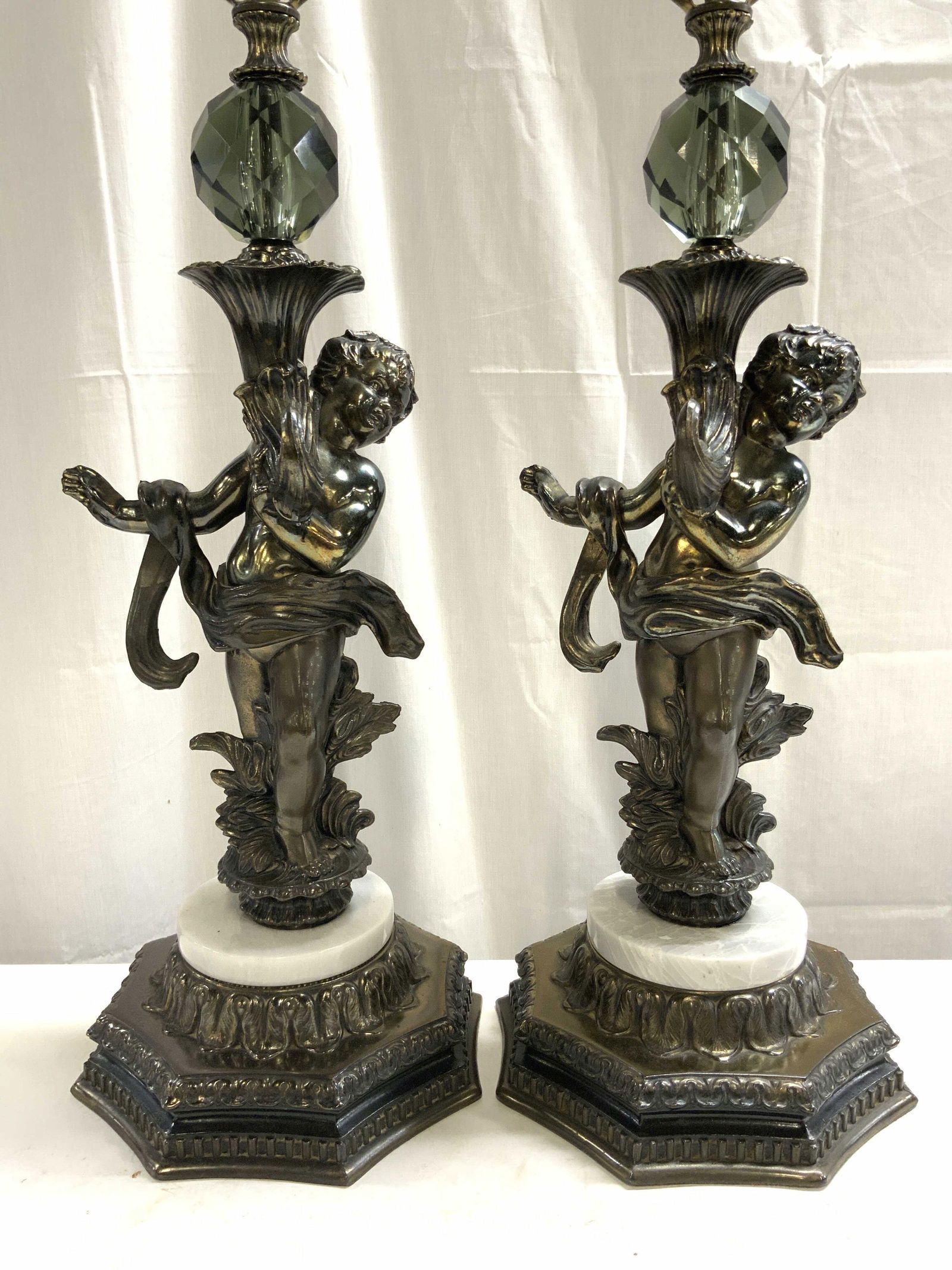 Pr Bronzed & Marble Art Nouveau Cherub Tbl Lamps: Lot includes 2 table lamps. Each are bronzed gilt metal with light slate toned marble areas. Lamps have cherub figures. Each lamp has smoky geometric glass structures. Lamps include harps and finials.
