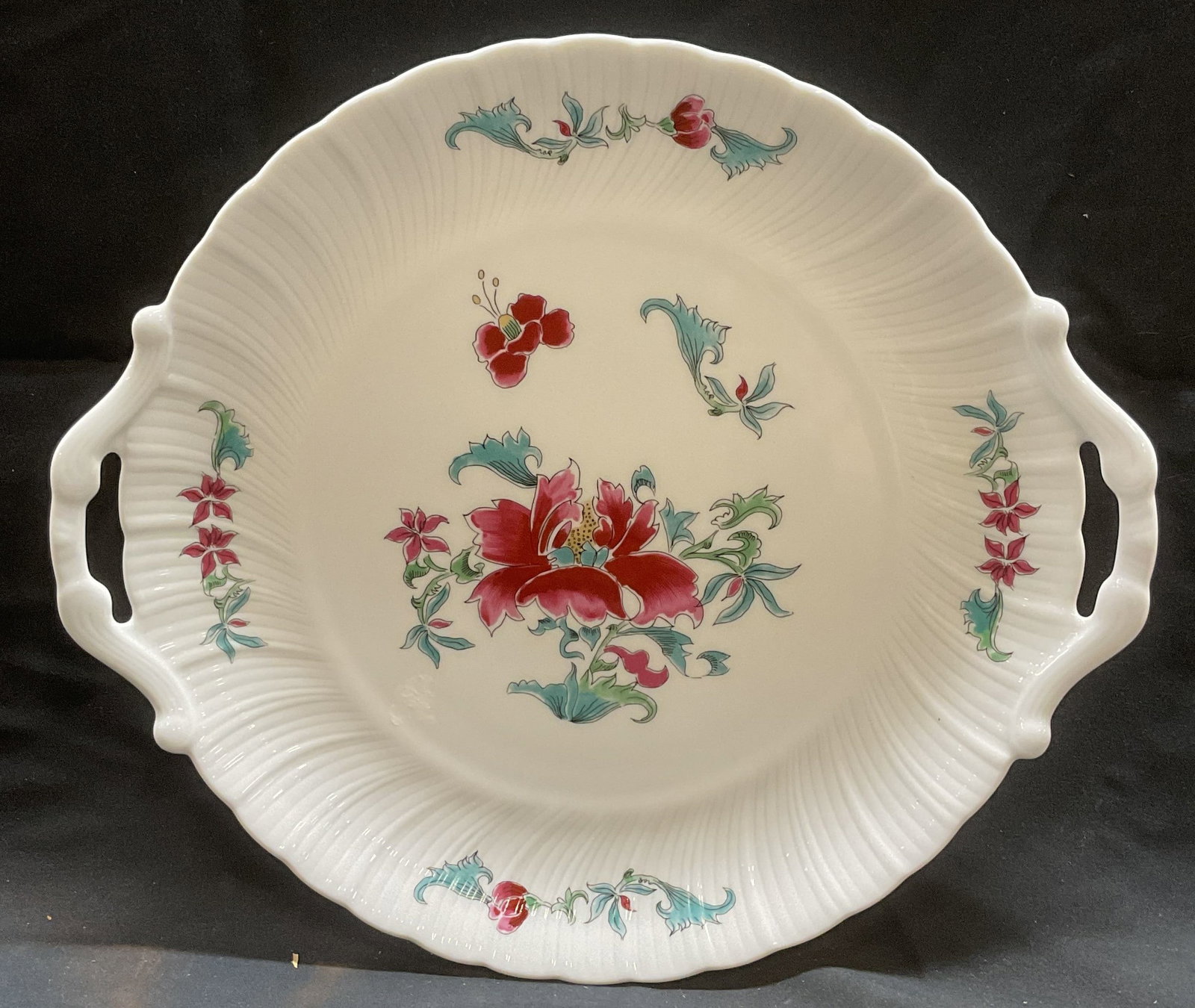 Limoges Porcelain Lhassa Flower Platter, France: Limoges porcelain platter with handles. Round shaped. Lhassa pattern with red floral motif. Signed on underside. Made in France. Measures approx 10.5 inches wide. Some wear consistent with exposure. L