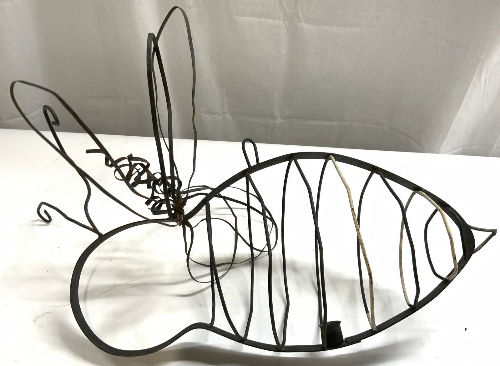 Vintage Hanging Metal Bumblebee Candle Holder: Candle holder is vintage. Piece is black toned and metal. Candleholder has bumblebee form. Piece has 1 candle area. Structure on top to hang. Piece measures approximately 24 inches long 12 inches tall