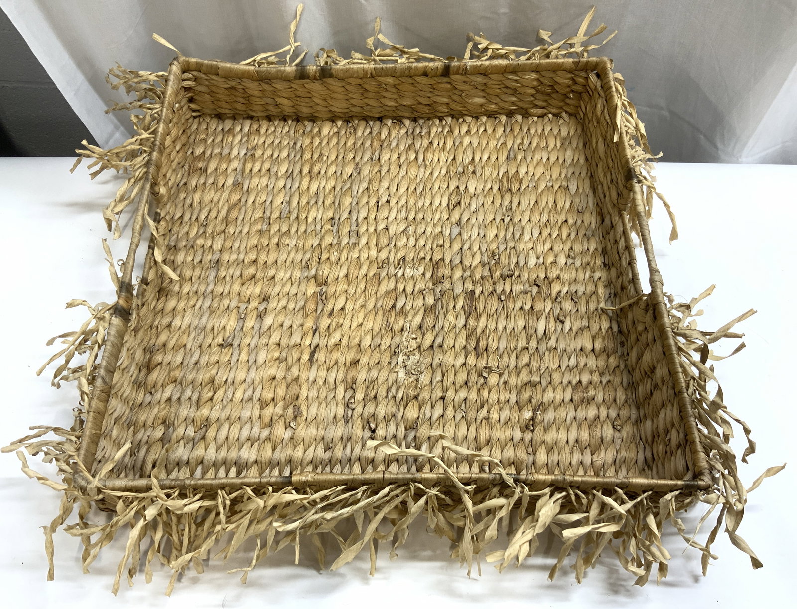 Woven Rattan Centerpiece Tray W Handles: Tray is woven rattan. Piece has square form. Tray has fringes to exterior. Tray has handles at 2 sides. Piece measures approximately 24 inches square 4.5 inches tall. Centerpiece, centerpiece tray, ra