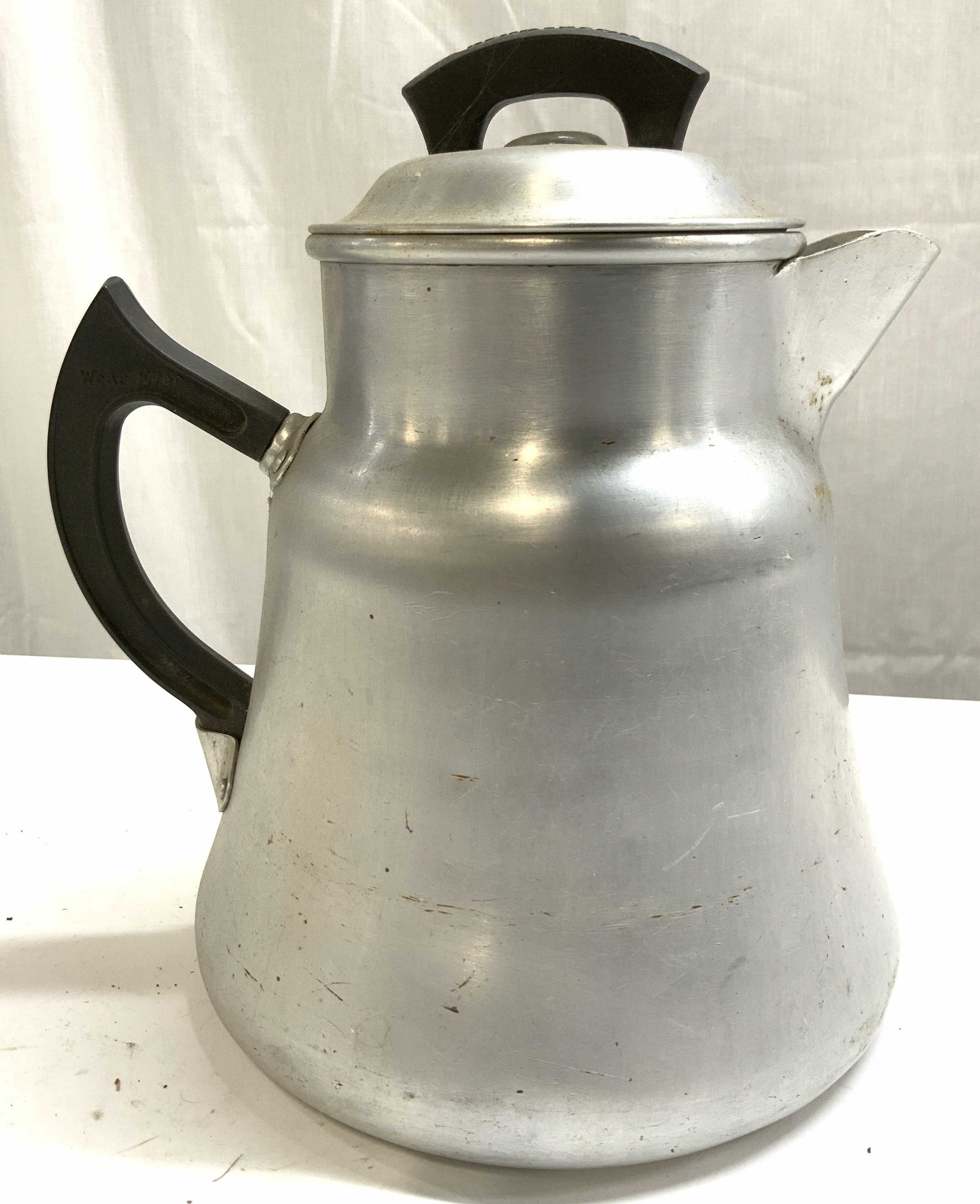 TACU CO Vintage Aluminum Teapot W Lid: Underside is inscribed TACU CO. Teapot is Vintage. Piece is aluminum as reads on underside. Handles read WEAR EVER. Teapot includes lid. Piece measures approximately 9 inches tall 8 inches deep 6.5 in