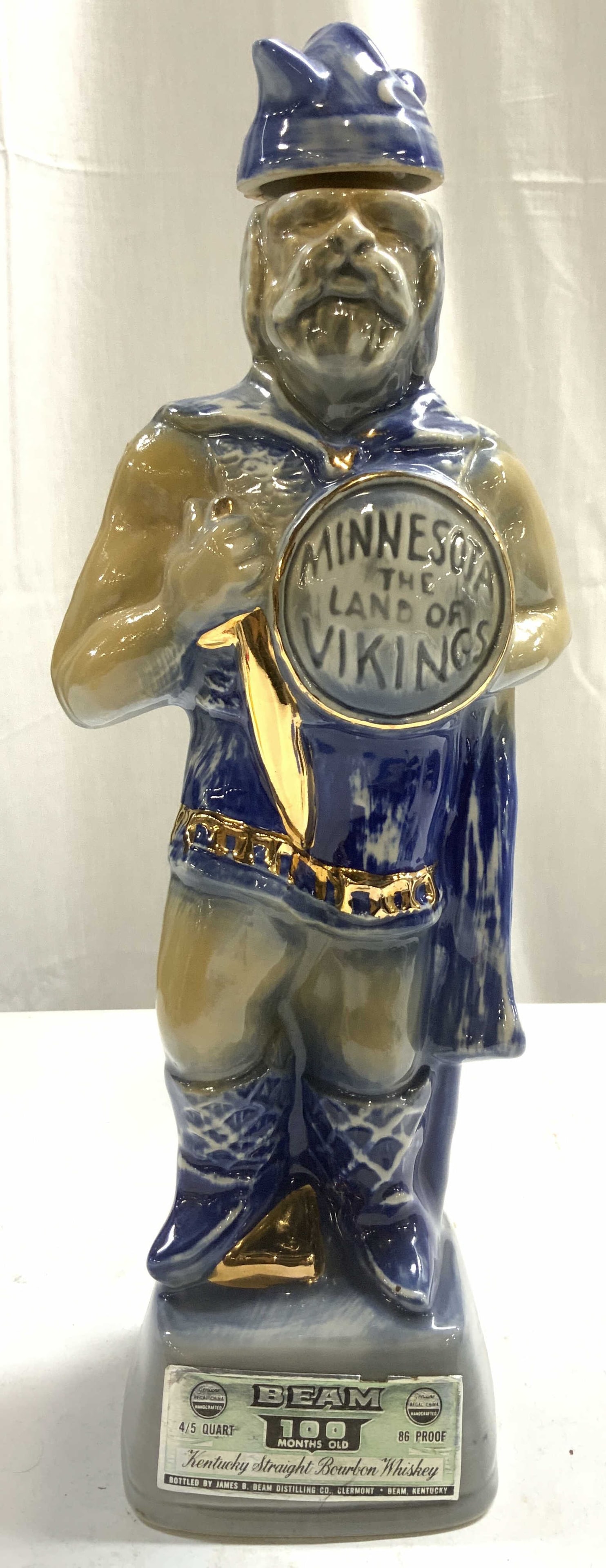 JIM BEAM Minnesota Land Of Vikings Ceramic Decanter: Tag reads JIM BEAM, Piece is vintage and ceramic. Decanter depicts male Viking figure, shield reads MINNESOTA LAND OF THE VIKINGS. Figure has some gilt areas. Decanter includes stopper and stamp. Piec