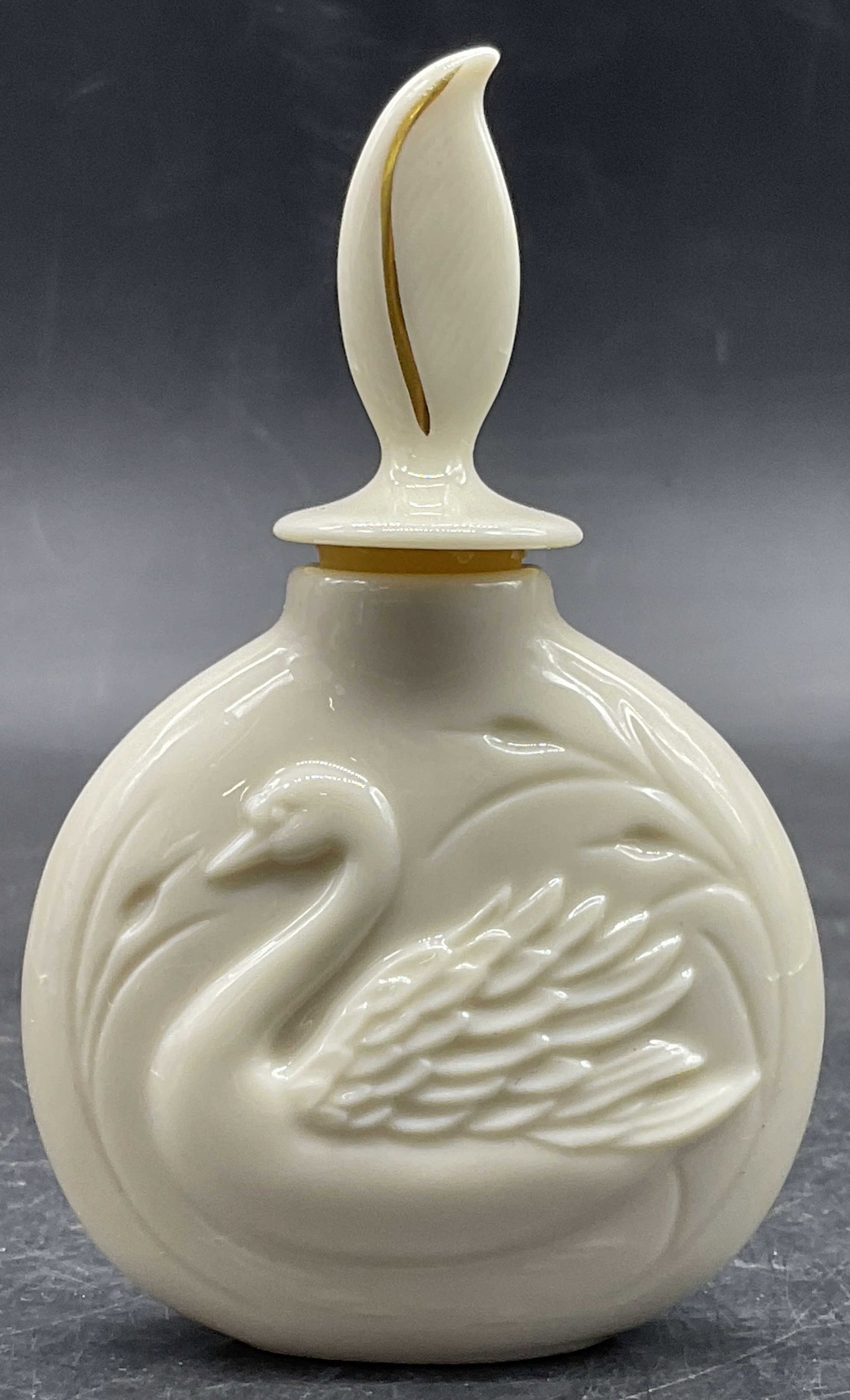 LENOX USA Porcelain Swan Motif Perfume Bottle, Lid: LENOX USA Porcelain Swan Motif Perfume Bottle. Lidded. Measures approx. 4H x 2.5W in. Rubber stopper to the lid. Gilt accent to the lid. Underside signed LENOX, MADE IN USA. Surface wear consistent wi