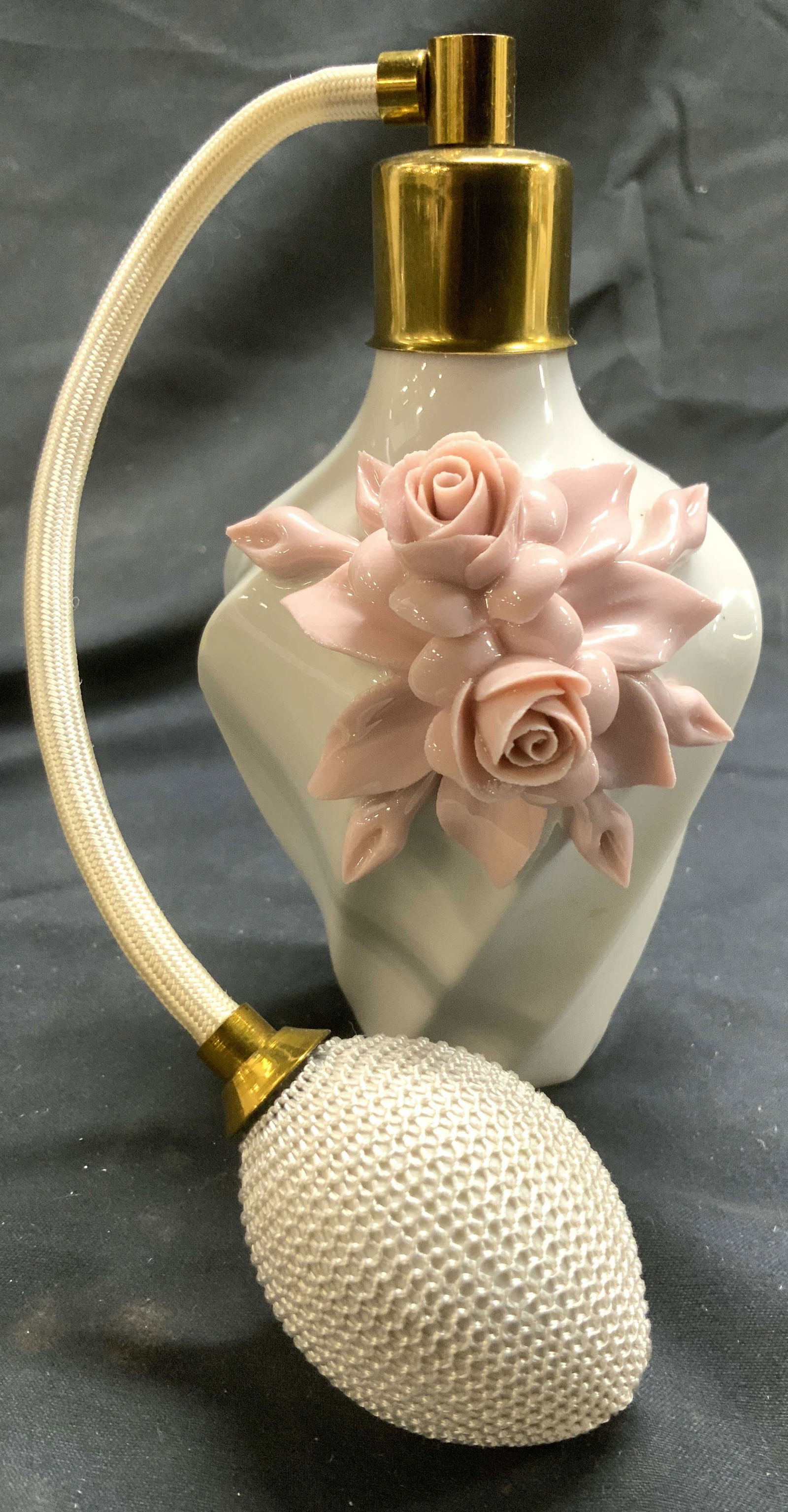CAPODIMONTE Porc Perfume Bottle W Puff Atomizer: Underside has CAPODIMONTE Trademark. Perfume bottle is white toned and porcelain with pink toned floral detail. Piece has puff atomizer. Top of piece is gilt metal. Perfume Bottle measures approximate