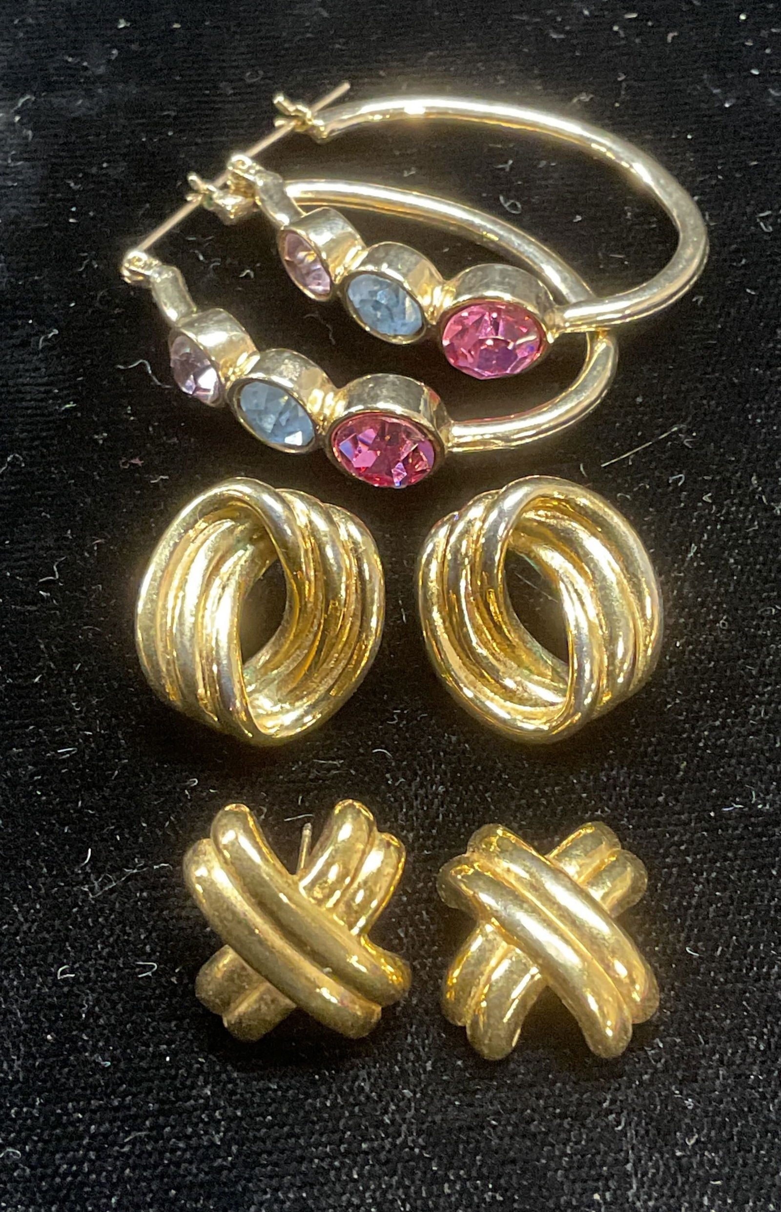 Lot 3 Monet Gold Tn Earrings, Crystal Earrings: 2 pairs of vintage Monet gold tone X and open circle cable earrings. Post backing. One piece needs repair. Both signed on undersides. Gold tone pink and blue crystal hoop earrings. Post backing. Large