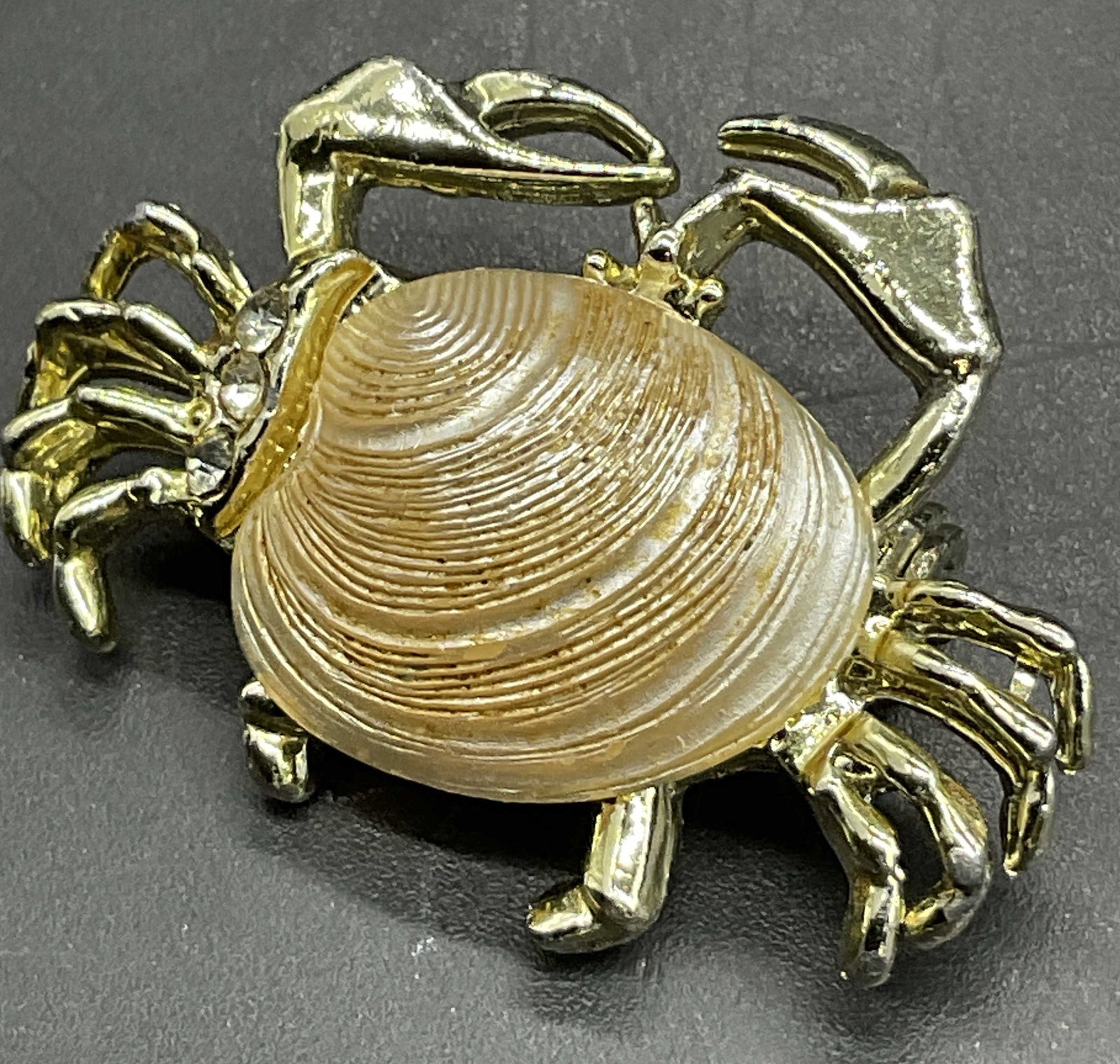 Vintage Seashell Crab Form Figural Brooch: Vintage Seashell Crab Form Figural Brooch. Crafted from gold tone metal and accented by a seashell & faceted crystals. Metal pin closure to reverse. Measures approx. 1.25W x 1L in. Surface wear and di
