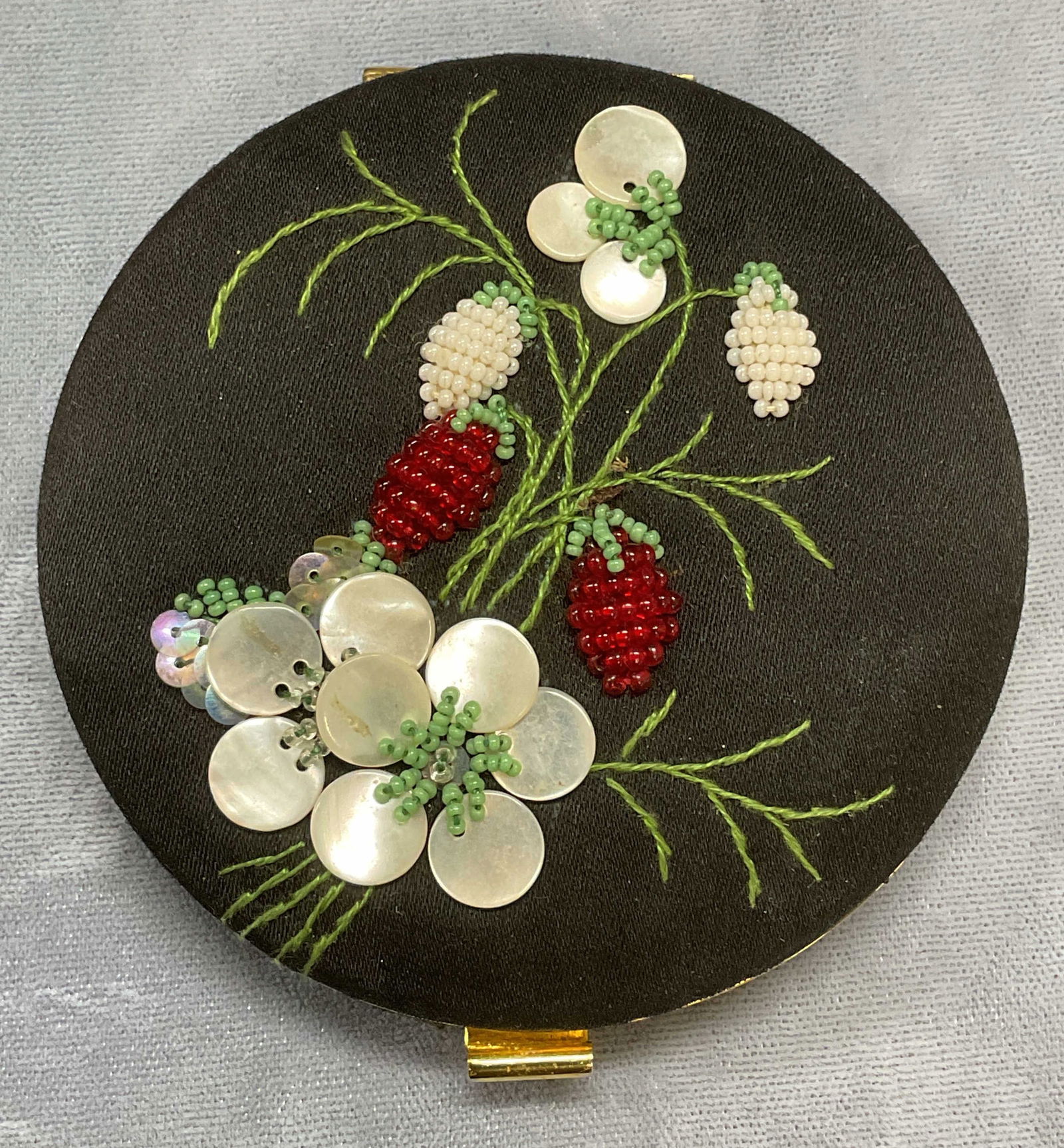 Vtg Black Silk Beaded Makeup Compact, France: Vintage gold tone black silk covered makeup compact. Beaded and mother of pearl decoration with floral design. Made in France. Measures approx 3 inches wide. Some wear including scratching and residue
