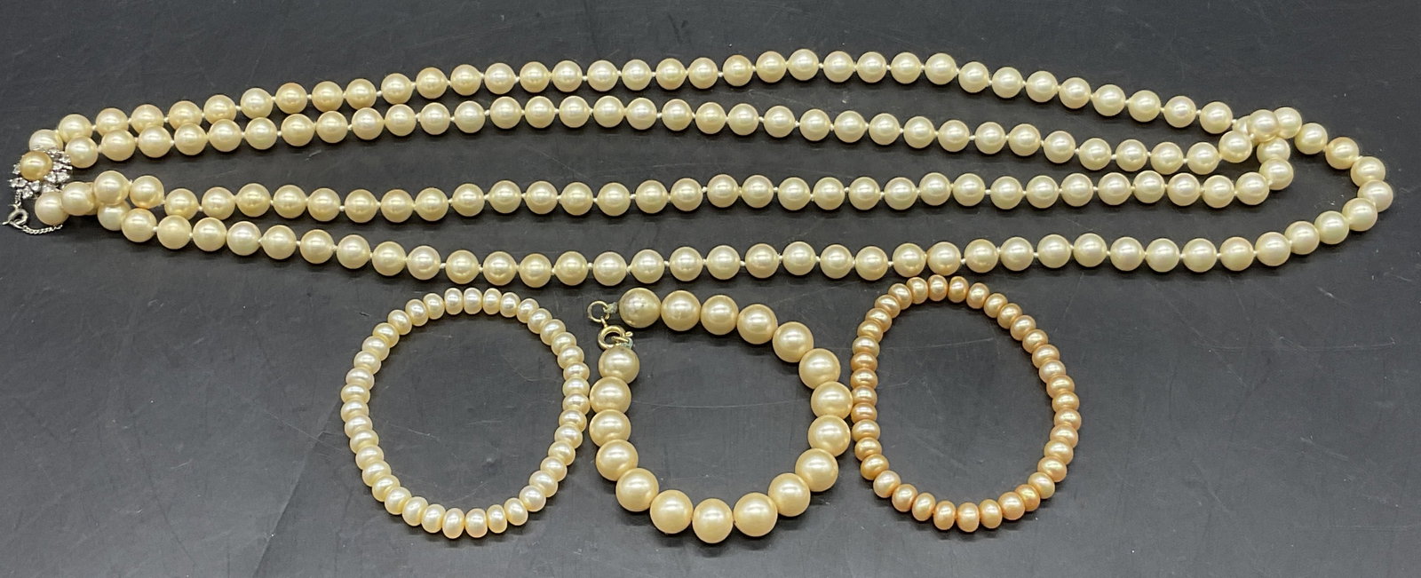 Lot 4 Vintage Pearlescent Necklace & Bracelets: Vintage pearlescent bracelets and a double strand necklace. Three bracelets, one necklace. The necklace secures with a box clasp closure and a safety chain. Necklace length measures approx. 27 inches.