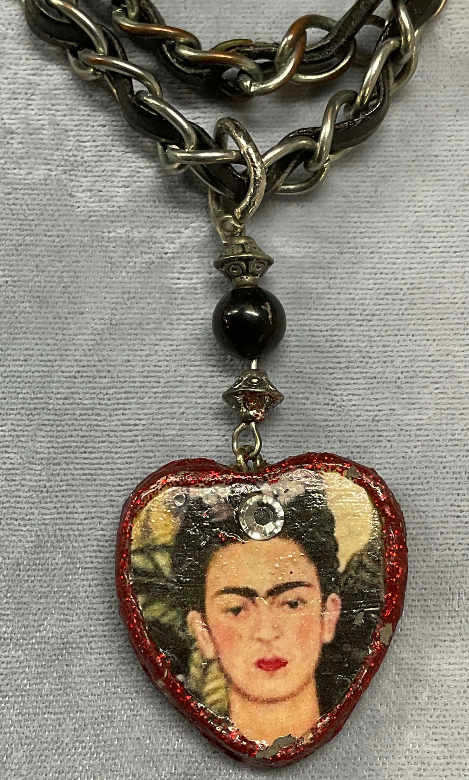Vintage Silver Tone Frida Kahlo Pendant Necklace: Vintage silver tone and black fabric woven chain necklace with handmade Frida Kahlo pendant. Drop length approx 11.5 inches. Pendant drop approx 2.5 inches. Some wear including scratching and losses o