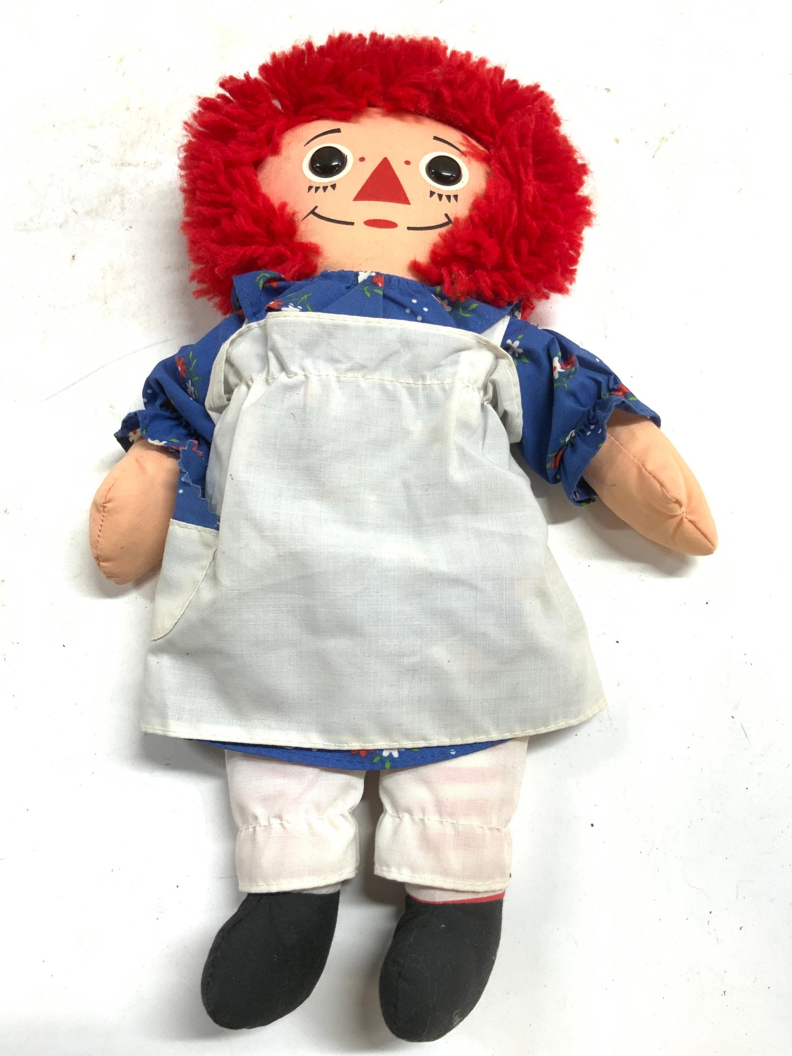 Playskool Vintage Raggedy Ann Doll: Doll appears to be Playskool. Piece is vintage circa late 1980s. Raggedy Ann doll with red toned yarn hair. Blue floral dress with white toned smock & black toned shoes. Piece measures approximately 1