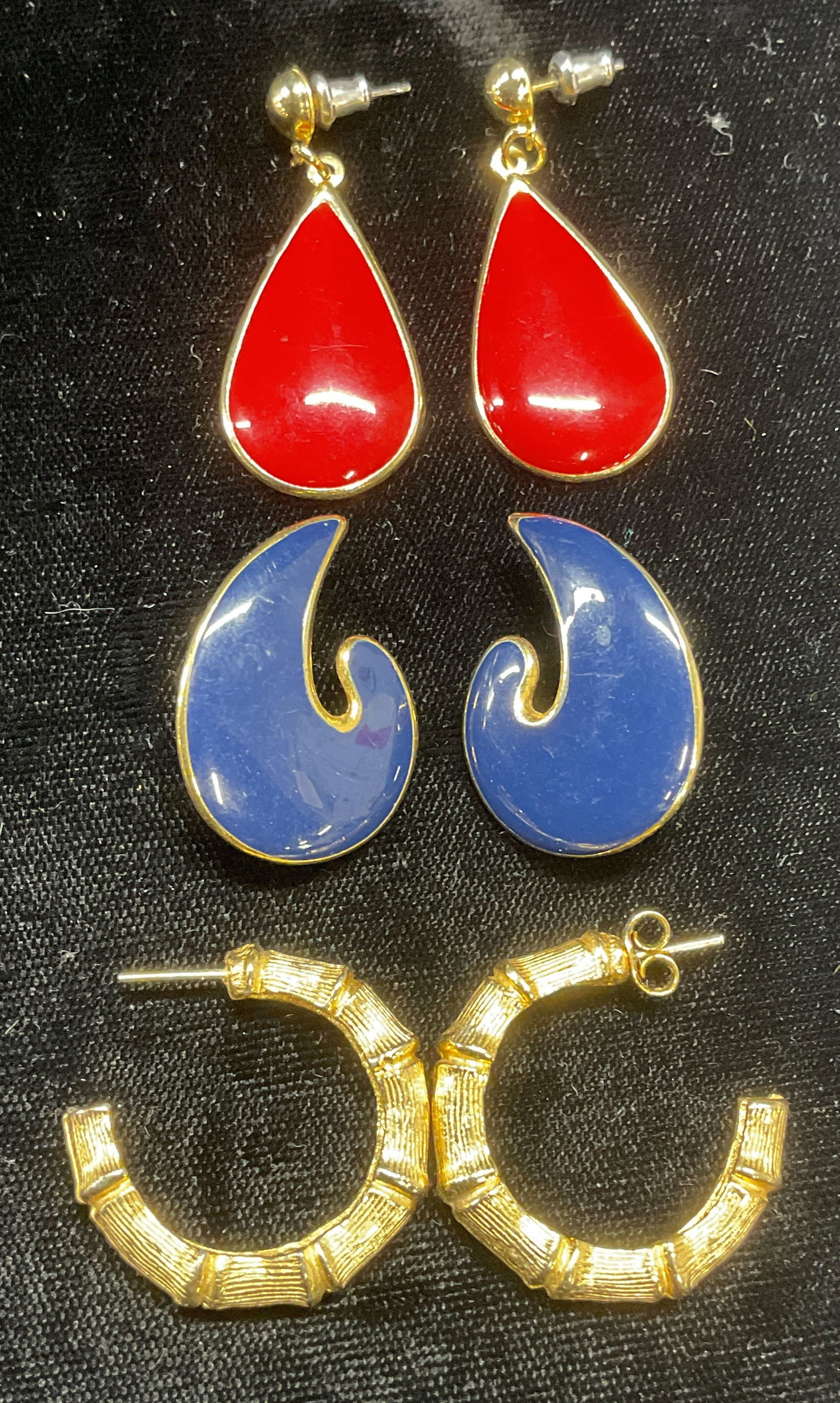 Lot 3 Gold Tone Enamel & Hoop Earrings: Lot of 3 pairs of gold tone earrings. Red enamel drop, blue enamel swirl, and bamboo motif hoops. Largest approx 1.5 inches long. Some wear to all including scratching observed. Jewelry, estate jewelr