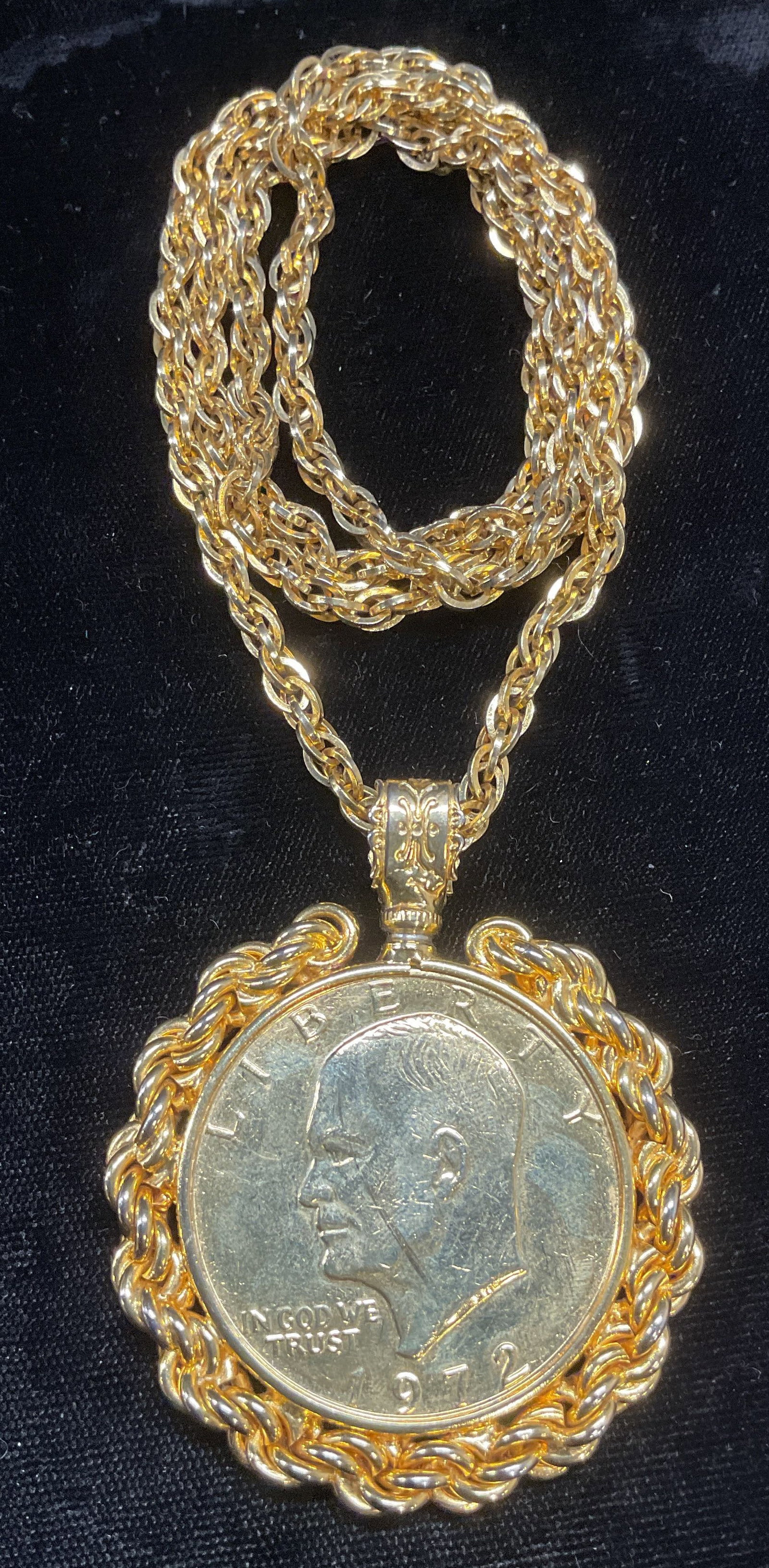 Gold Tone Eisenhower Dollar Coin Necklace: Gold tone Eisenhower dollar coin motif pendant with chain decoration on gold tone chains. Drop length approx 12.5 inches. Pendant approx 2.5 inches long. Some wear including scratching observed. Jewel