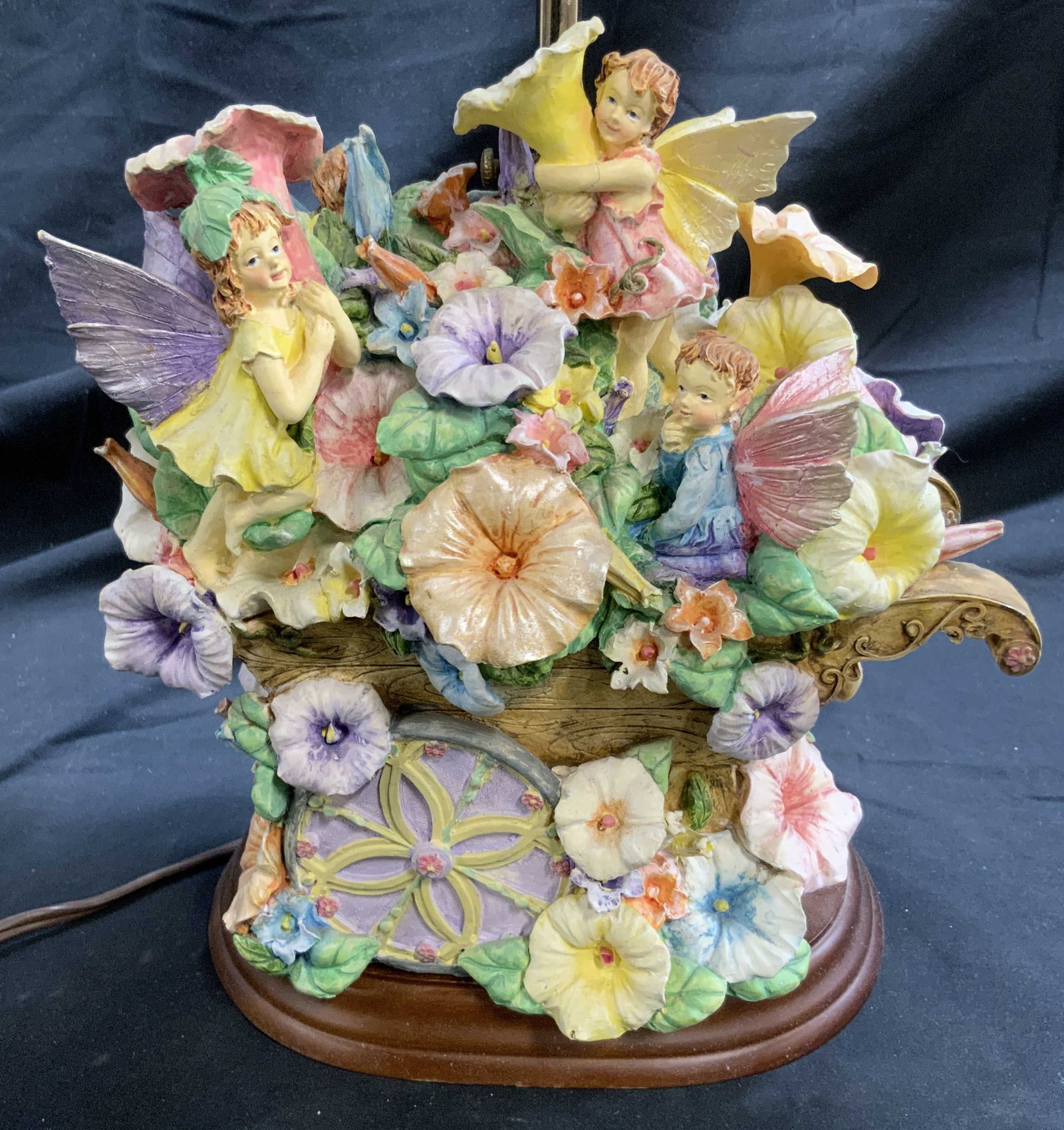 Composite Fairy & Floral Table Lamp W Shade: Table lamp with composite. Piece has fairy, floral, and leaf detail with ping wheelbarrow. Table has cream toned shade. Piece has gilt metal finial. Table lamp measures approximately 25 inches tall 7.