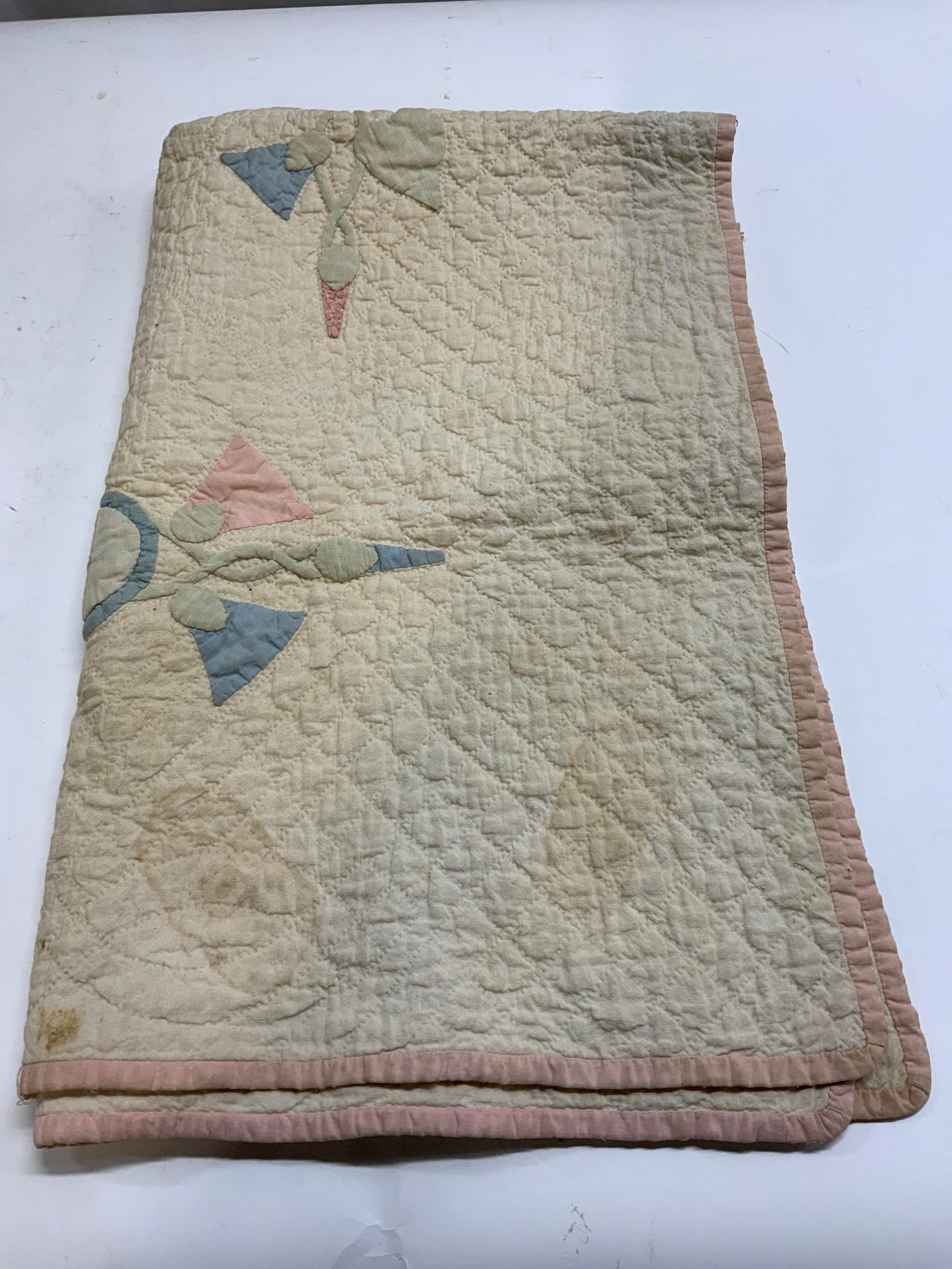 White & Pink Baby Quilt: White & Pink Baby Quilt. Baby quilt with a pink border, it also has a unique embroidered design throughout the quilt. Such as pink & blue triangle/circle shapes. Very noticeable stains on quilt, appea